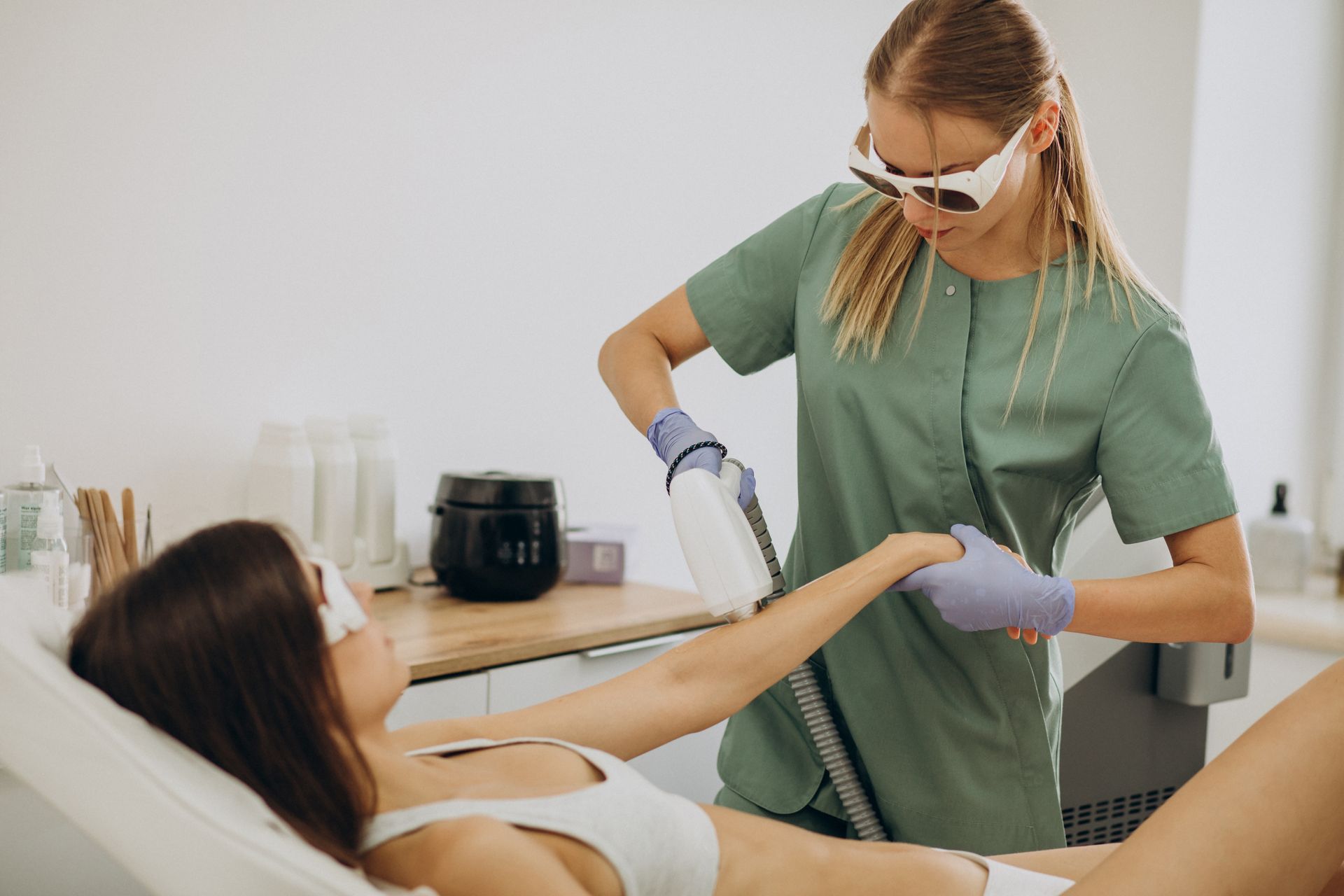 A woman is getting a laser hair removal treatment on her arm.