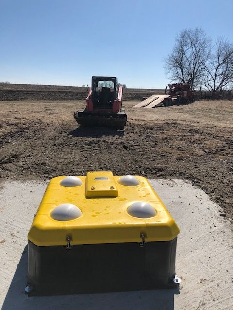 Yellow utility box on concrete pad with construction equipment in background.