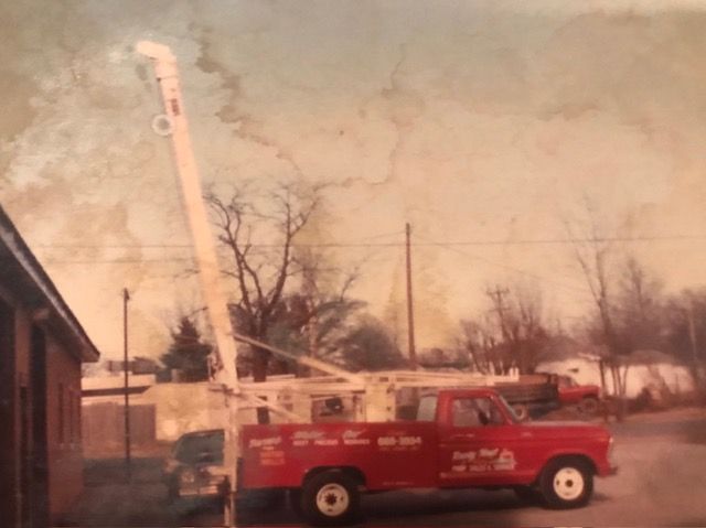 Red utility truck with a lift, parked near a building.