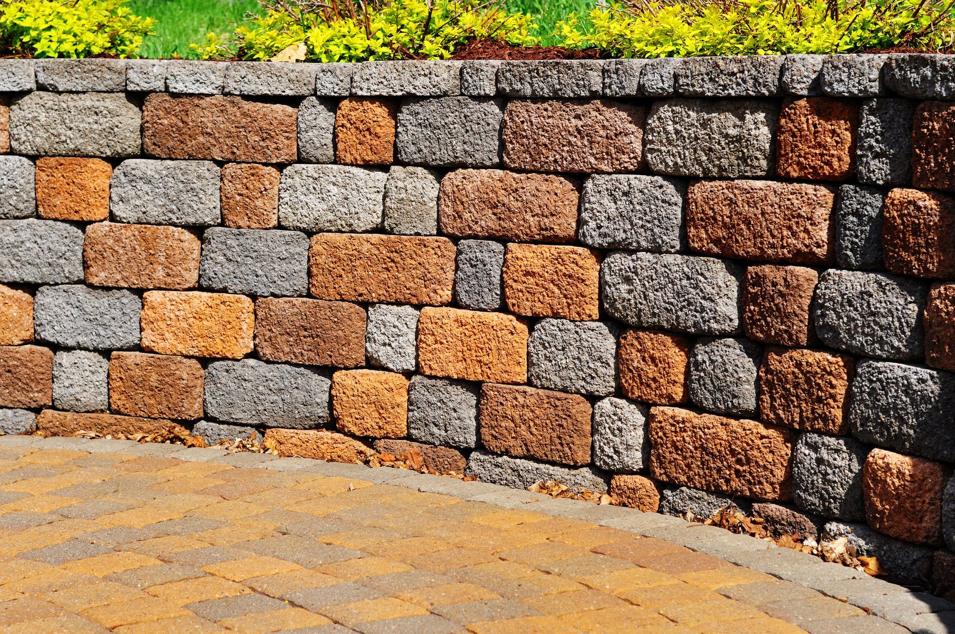 A brick wall with grass and bushes |Retaining Wall Installation in Barossa Valley 