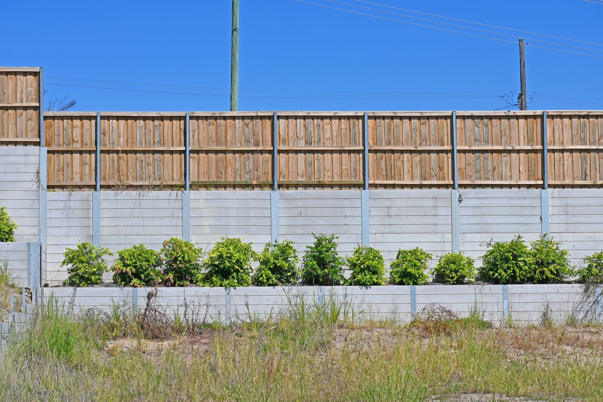 Concrete block retaining wall with a wooden fence.