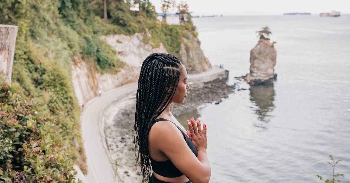 A woman is standing on a cliff overlooking the ocean.