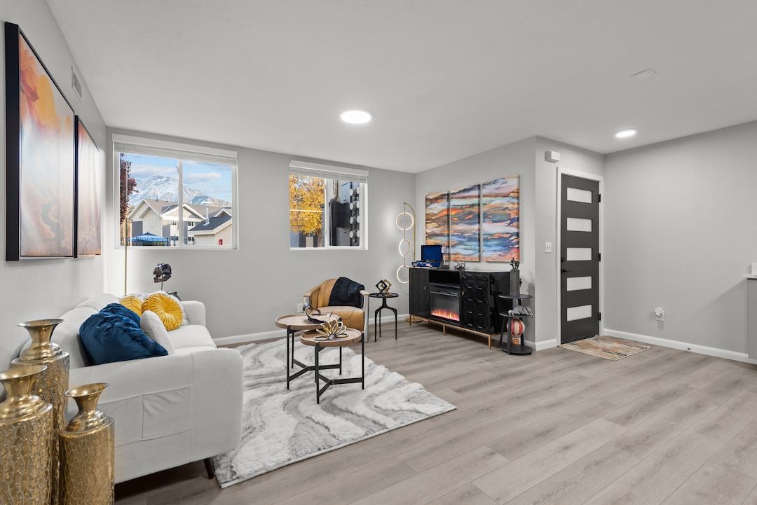 Bright modern living room with white sofa, gray rug, wall art, TV console, and wood flooring