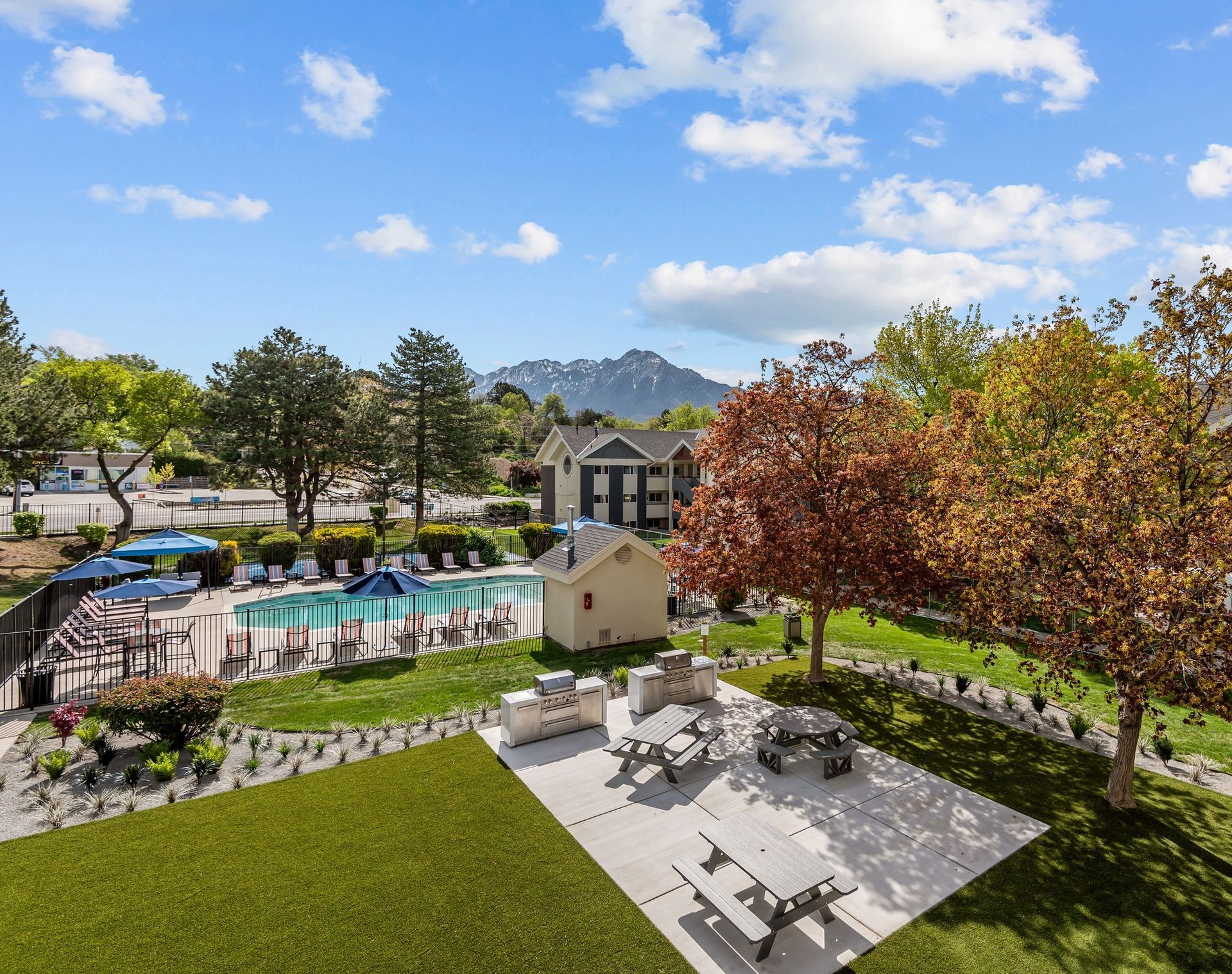 An aerial view of a backyard with a swimming pool and picnic tables.