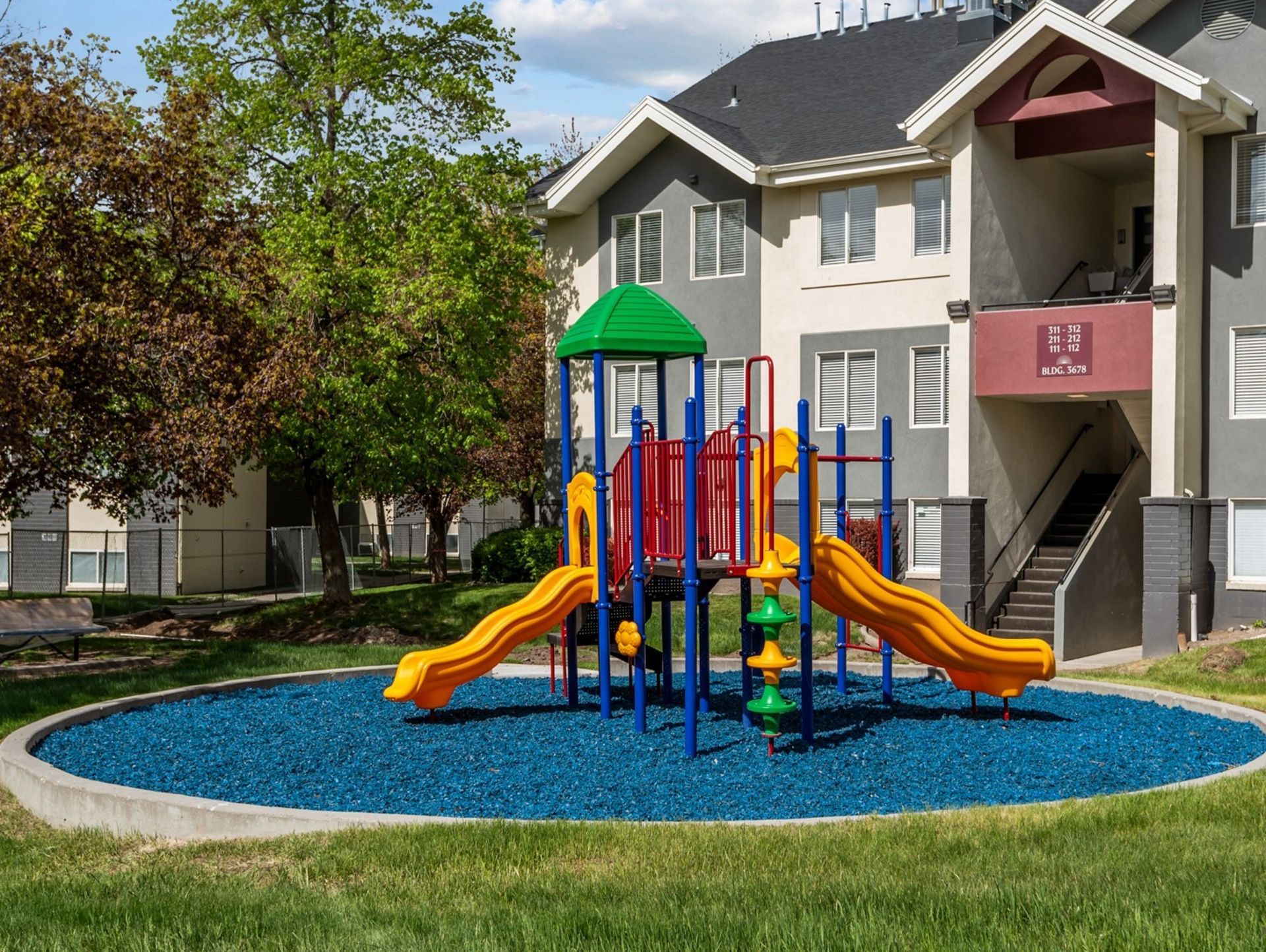 A playground with a slide and swings in front of a building.