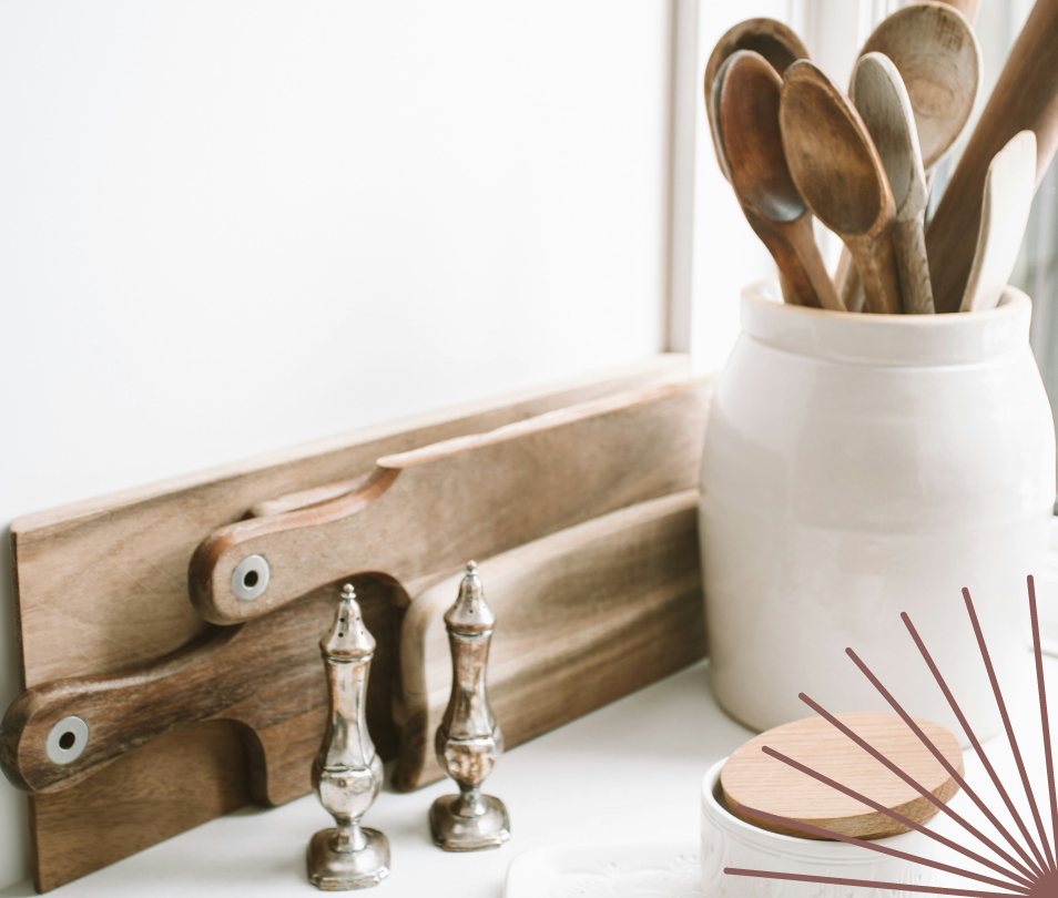 A wooden cutting board , salt and pepper shakers , and wooden spoons are on a table.