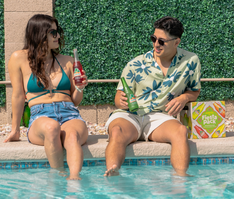 A man and a woman are sitting on the edge of a swimming pool.