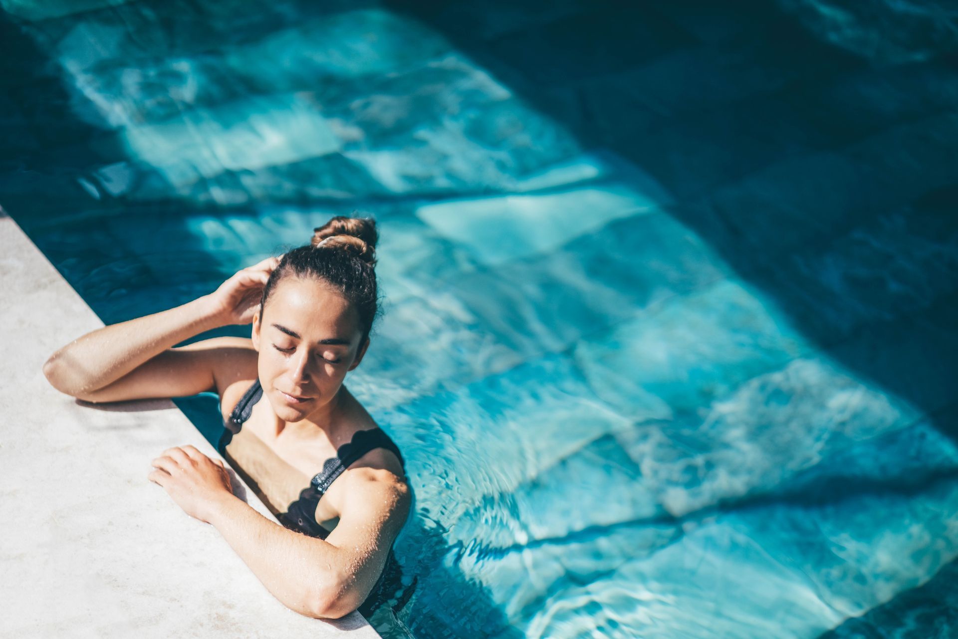 A woman is laying on the edge of a swimming pool.