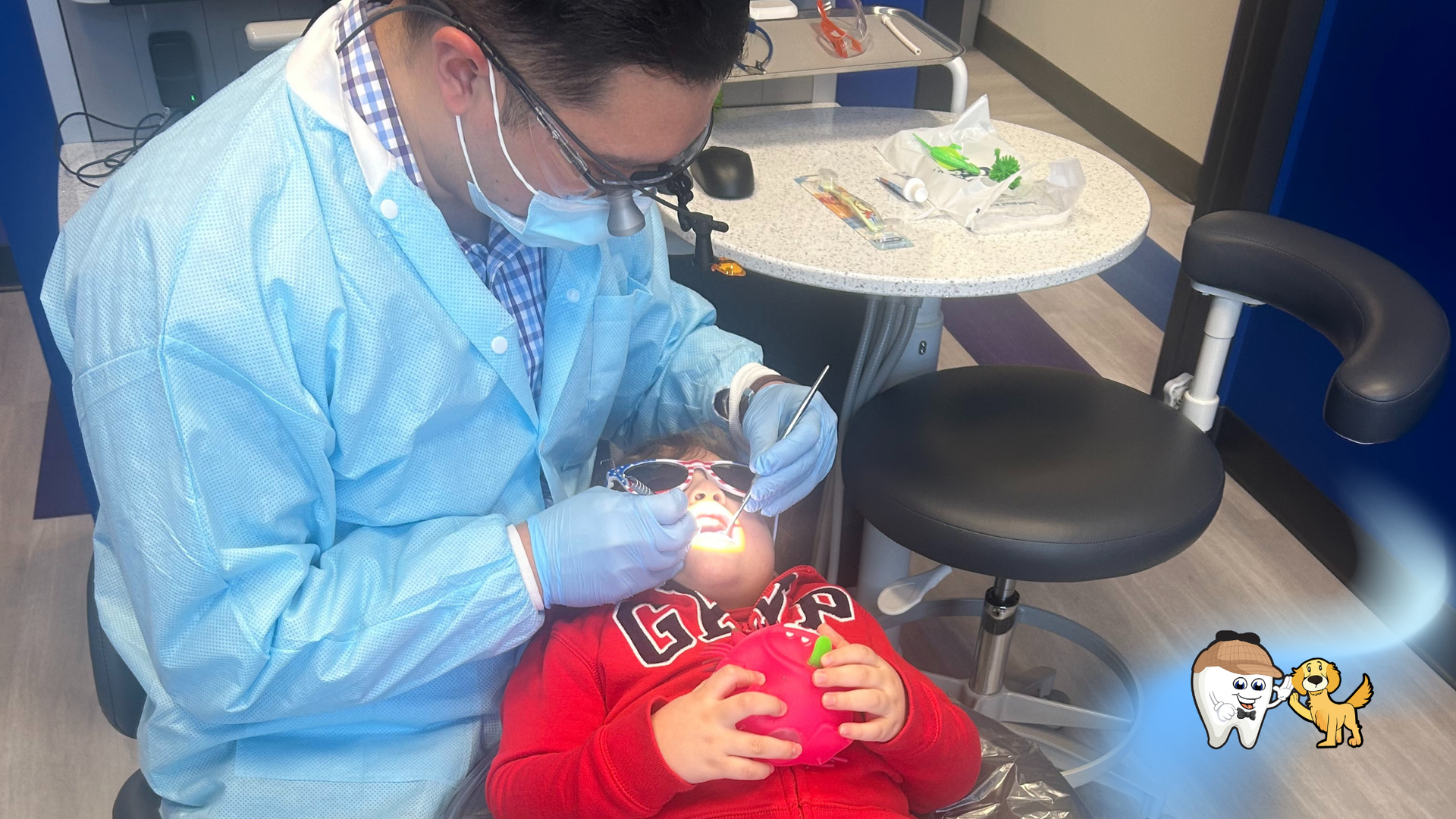 Dentist and young patient in dental chair, smiling, thumbs up. Dental office.