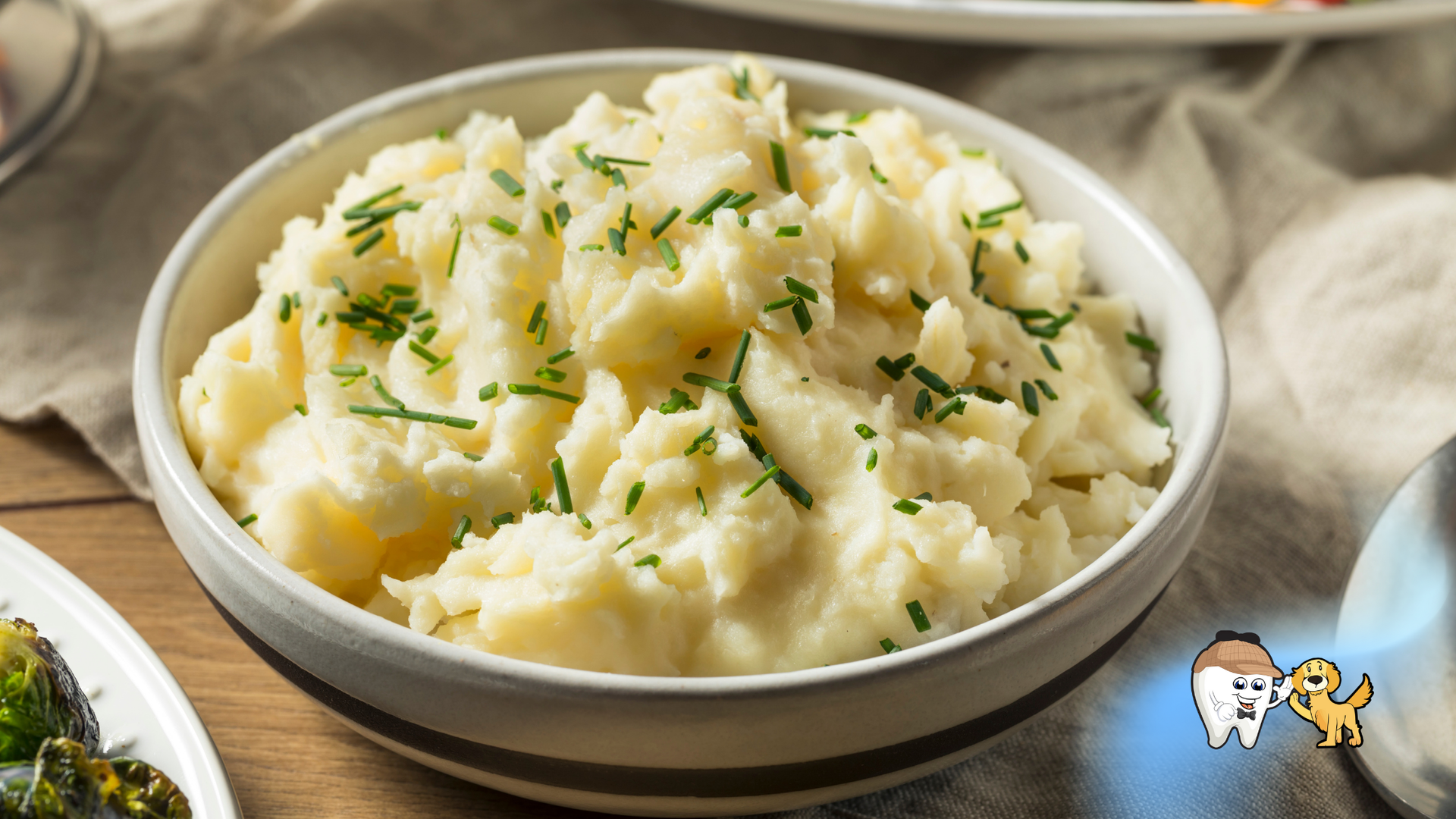 Bowl of creamy mashed potatoes, garnished with chives.