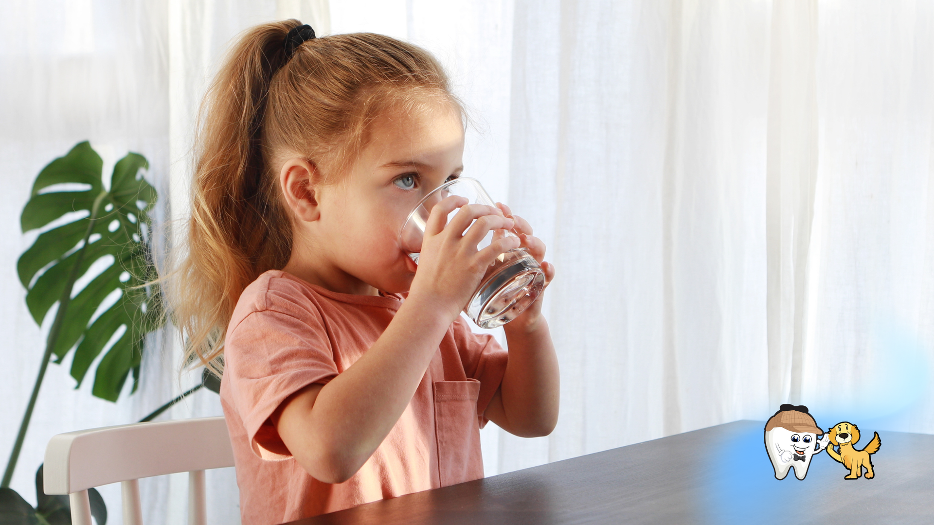 Girl with a ponytail drinking from a glass of water at a table indoors.