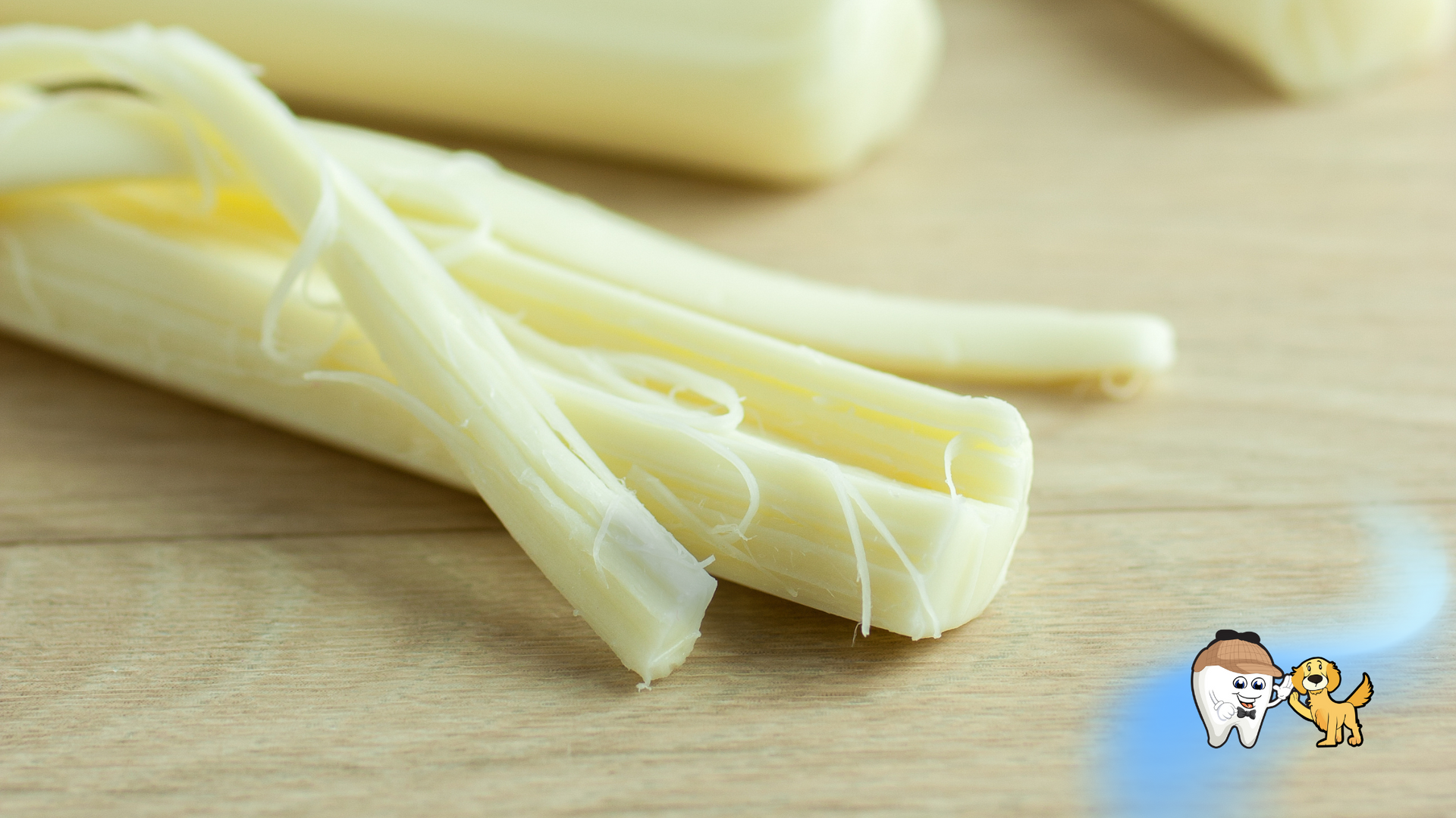 String cheese, peeled and shredded, on a wooden surface.