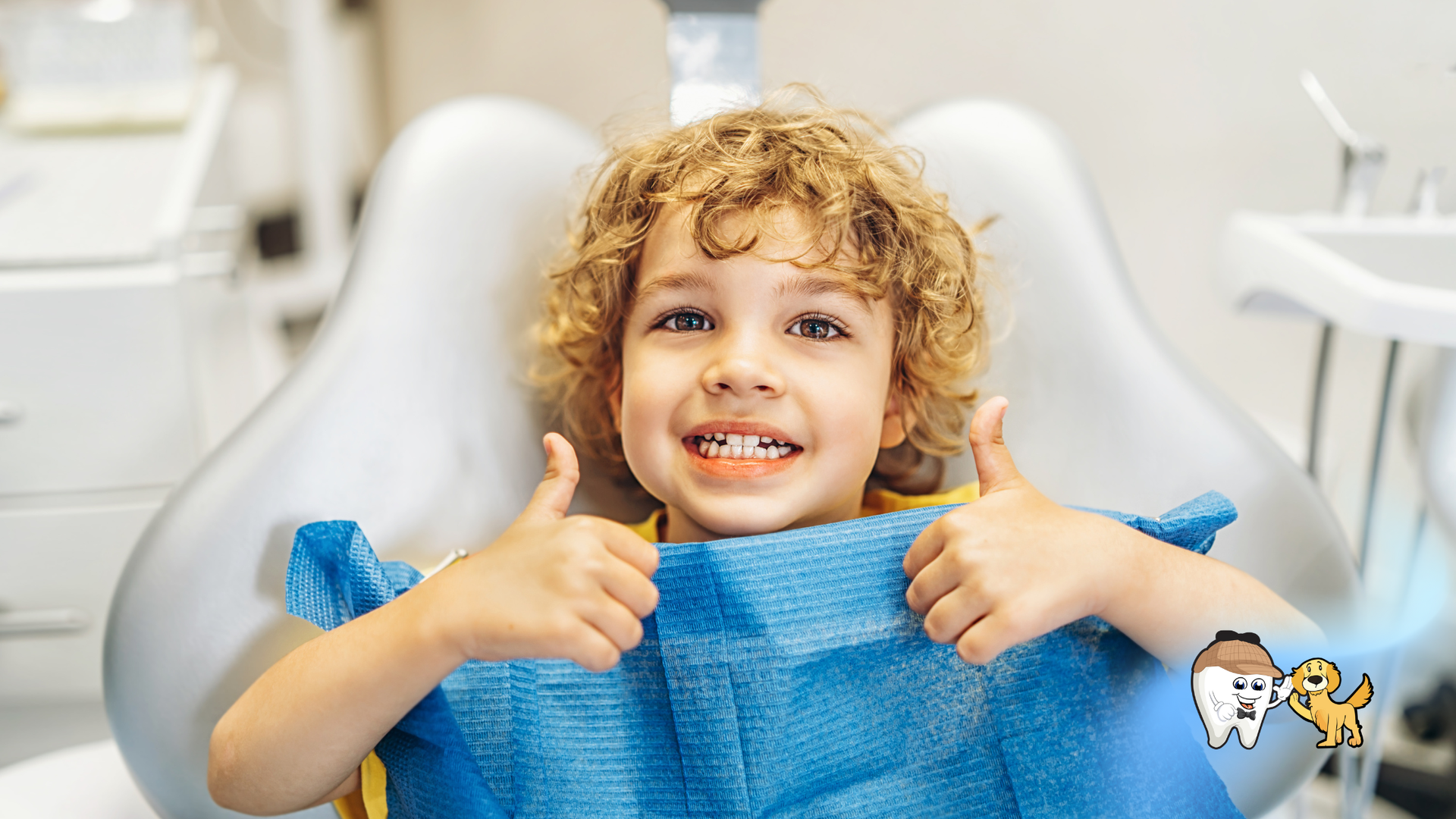 Young child with curly hair giving a thumbs-up while in a dentist's chair, wearing a bib, smiling.