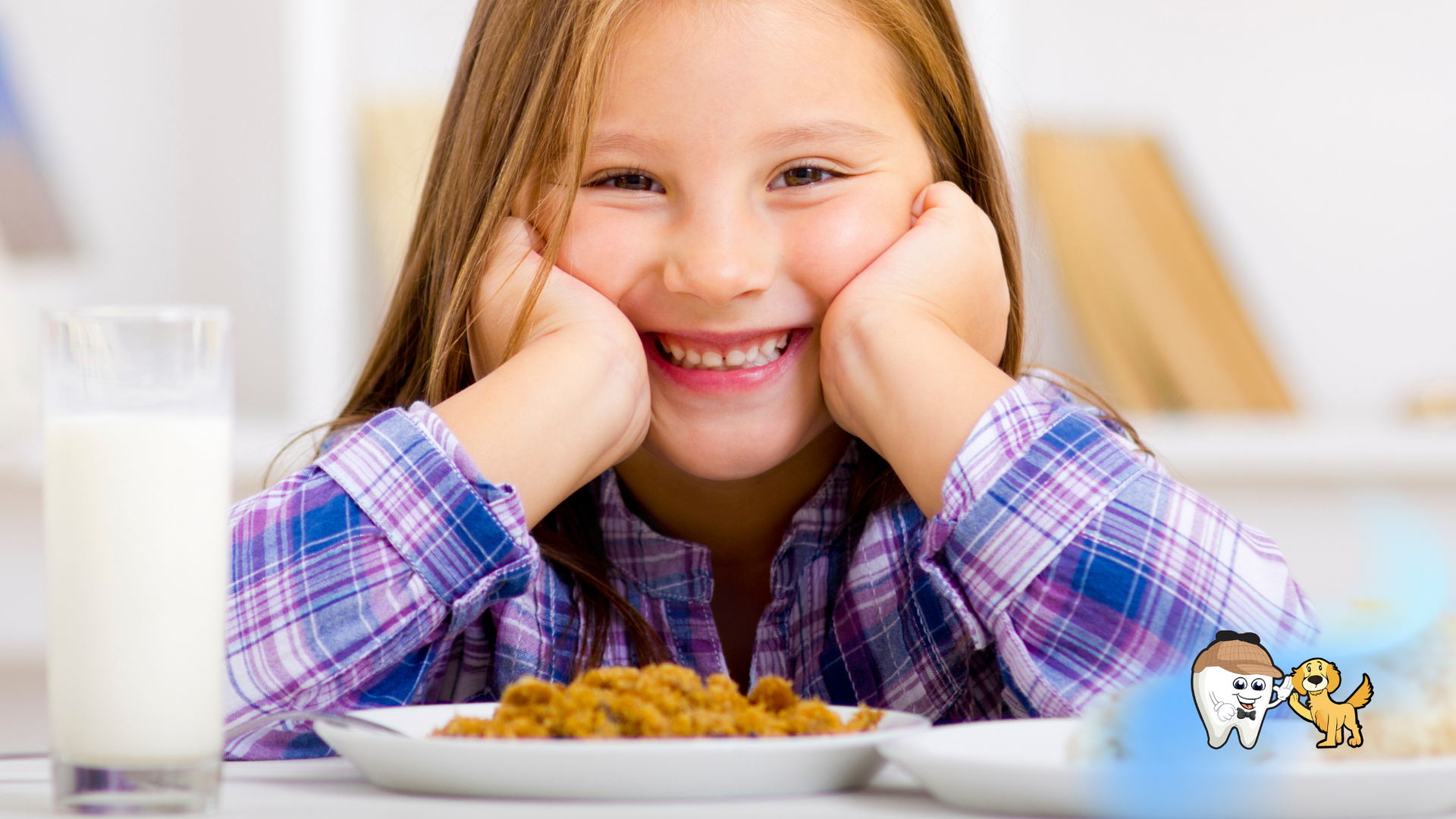 Girl smiling at a table with a glass of milk and a plate of food.