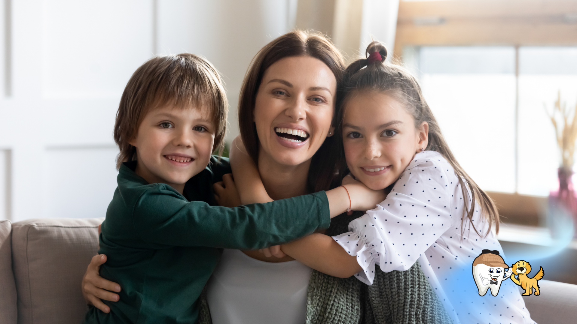 Woman with two children, all smiling and hugging on a couch indoors.