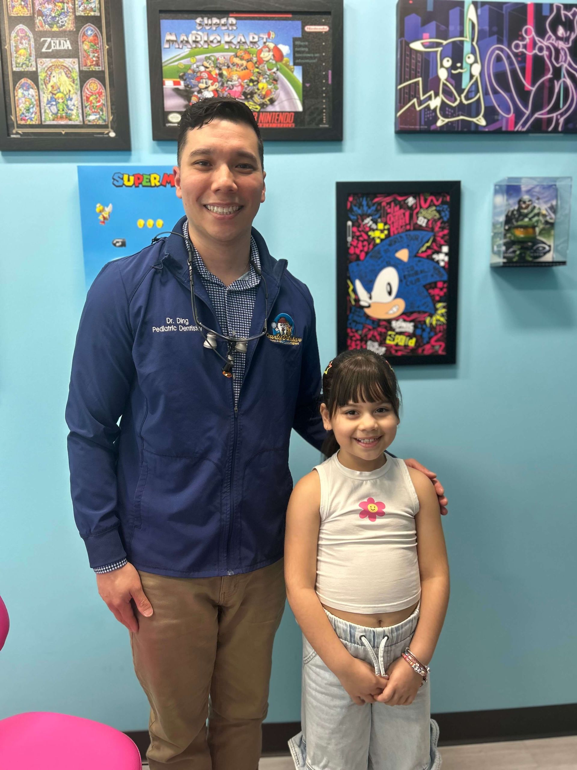 Man and child smiling, standing in a room with video game art on the walls.