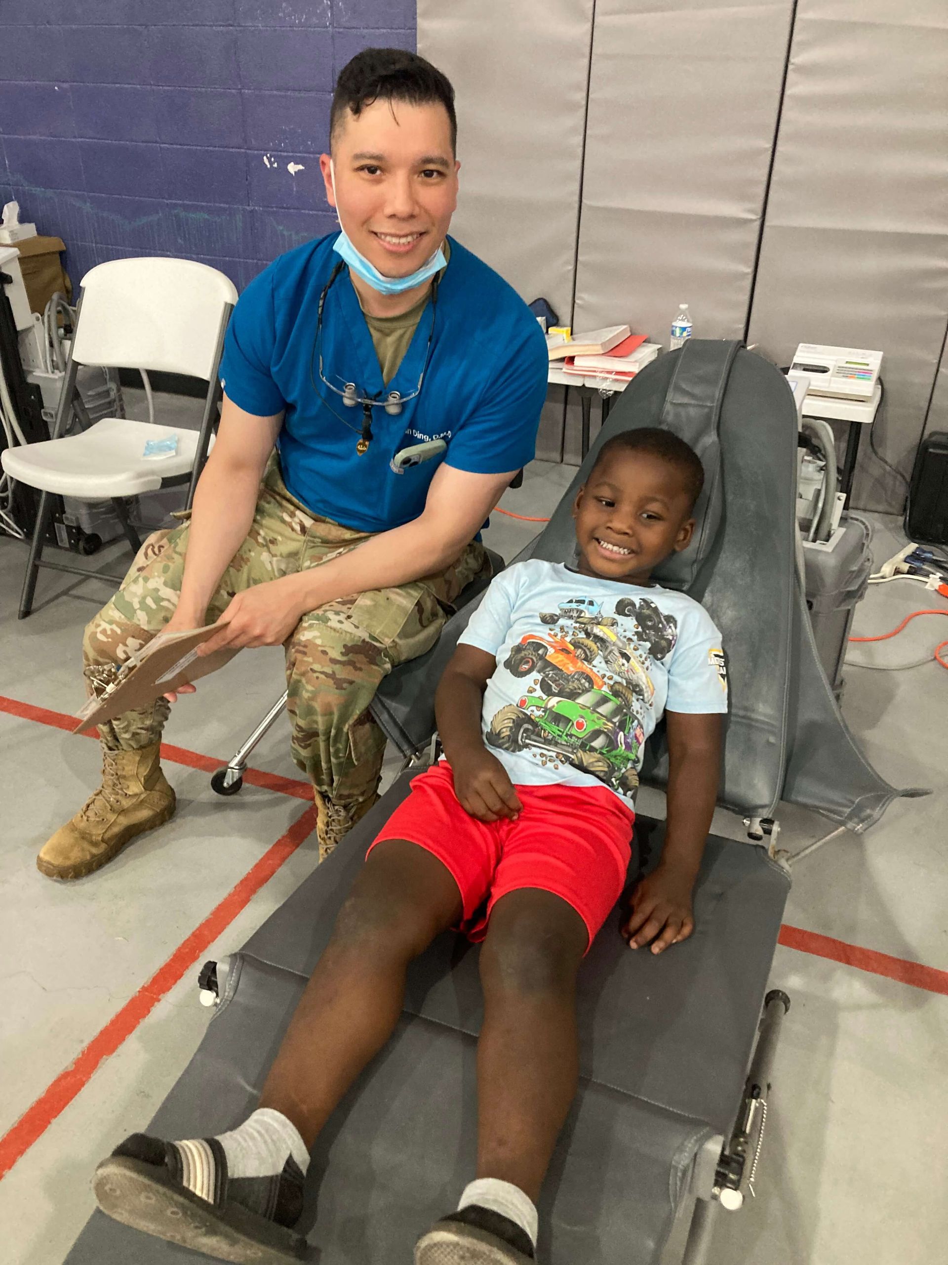 A smiling dental professional in uniform with a smiling child in a dental chair.