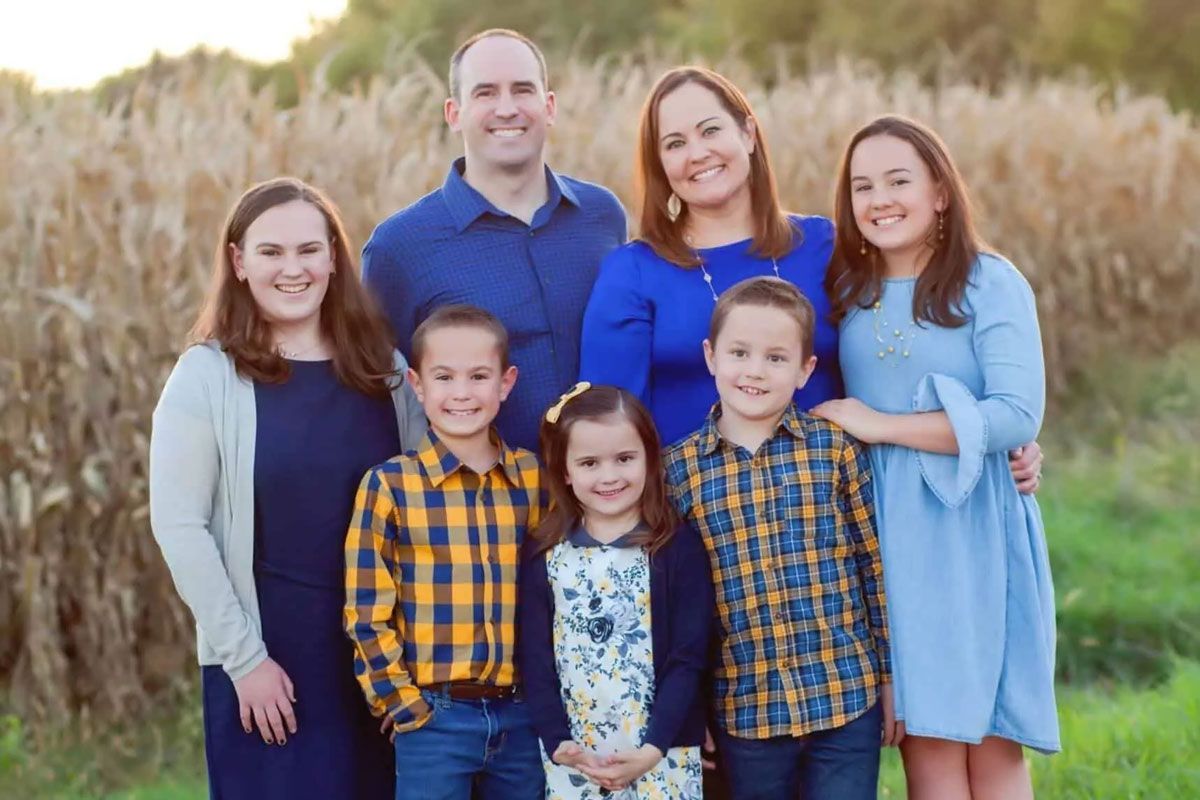A family is posing for a picture in a field of corn.