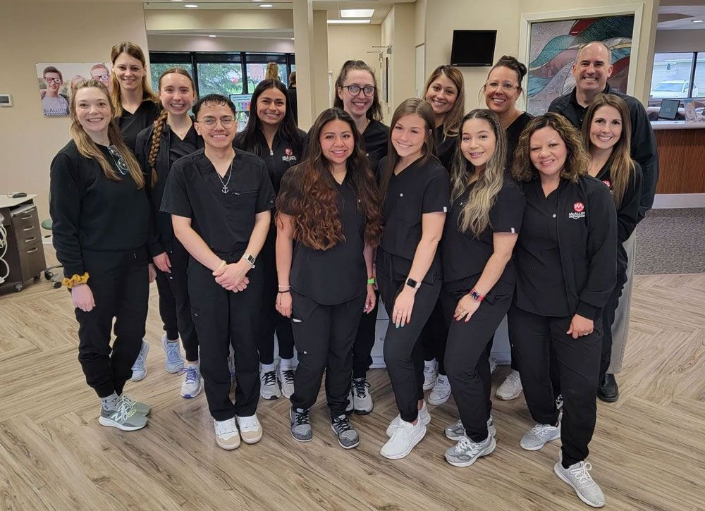 A group of people in scrubs are posing for a picture in an orthodontic office.