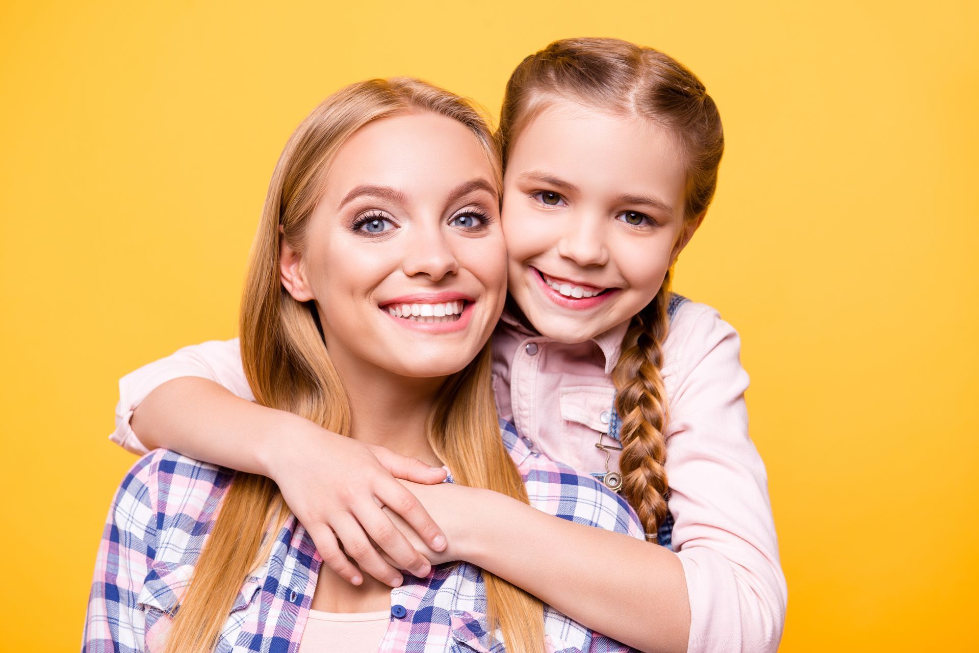 a daughter and a mother hugging in front of a yellow background