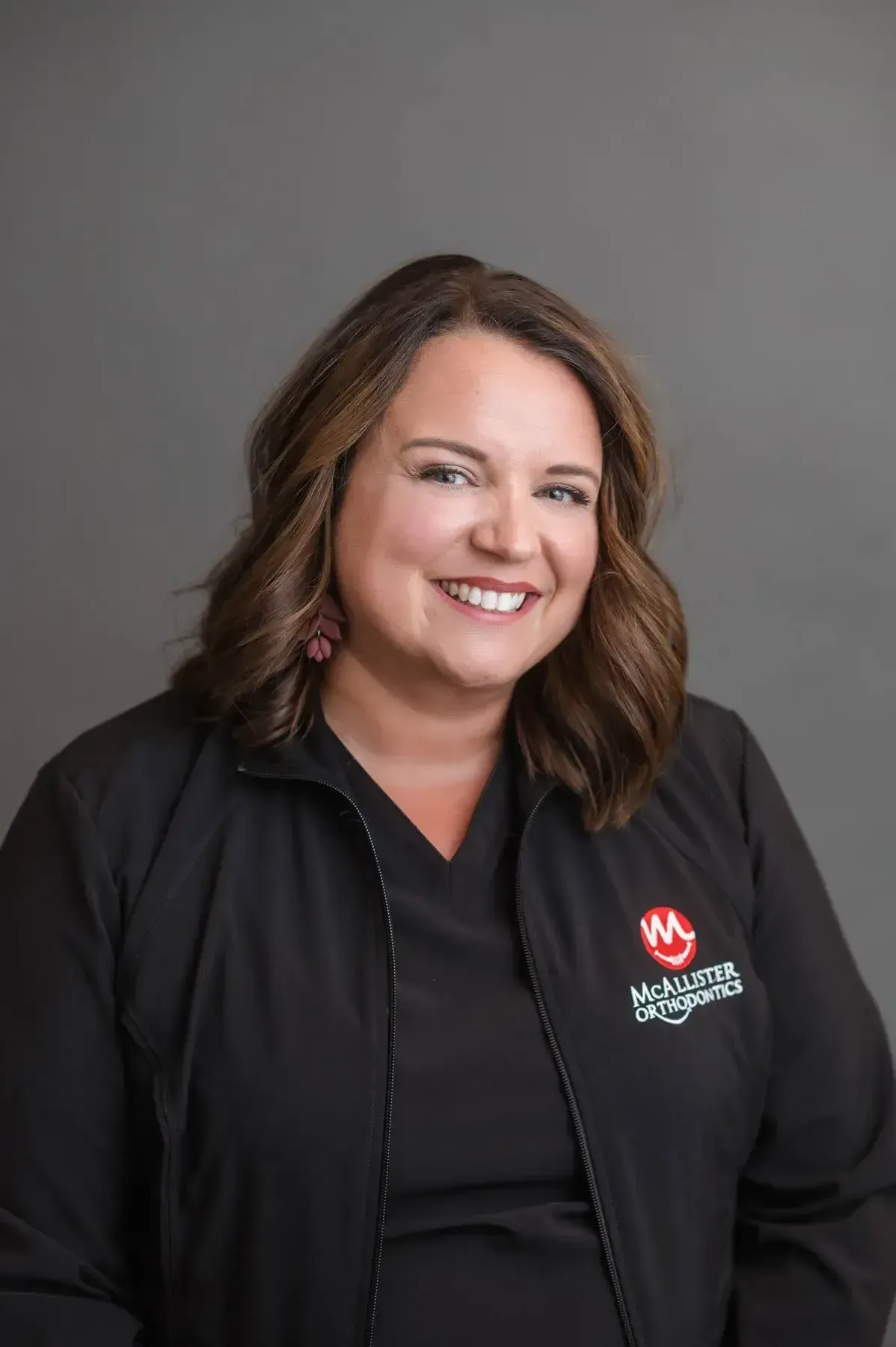 A woman is wearing a black jacket and smiling for the camera.