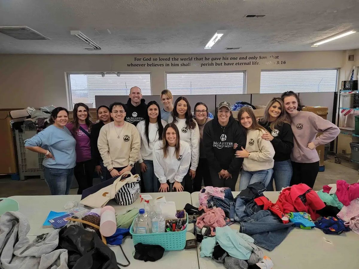 A group of people are posing for a picture in front of a table filled with clothes.