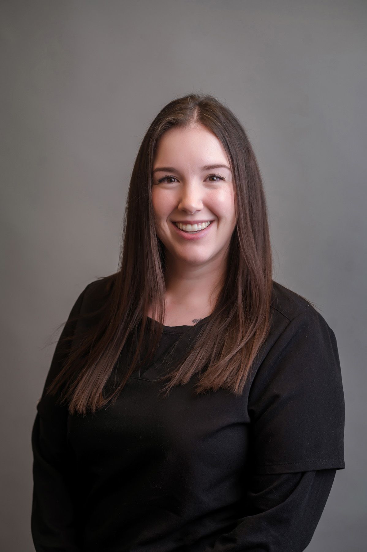 A woman is wearing a black jacket and smiling for the camera.