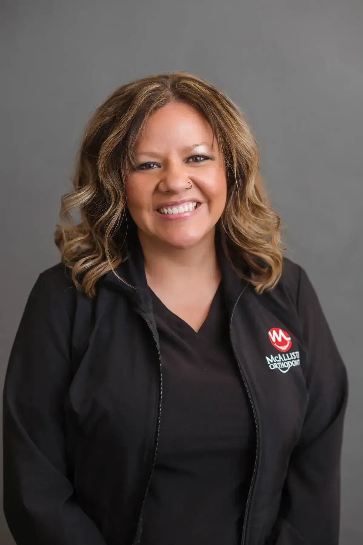 A woman is wearing a black jacket and smiling for the camera.