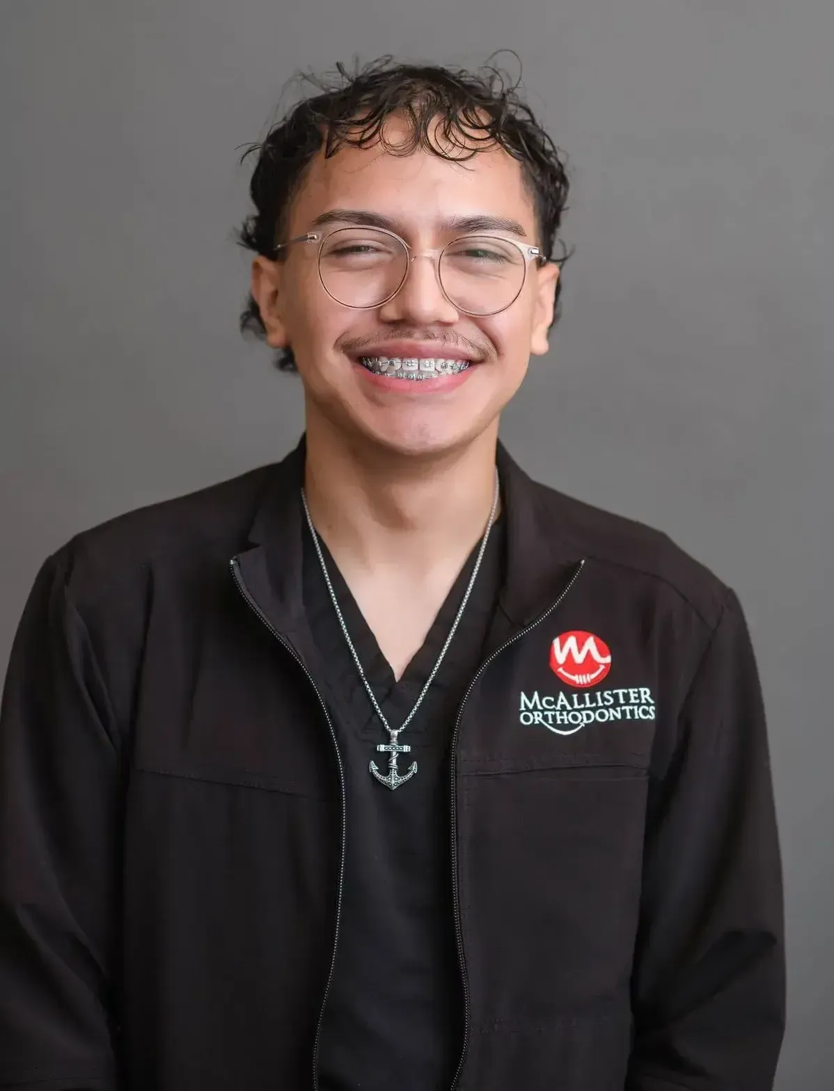 A young man wearing glasses and braces is smiling for the camera.