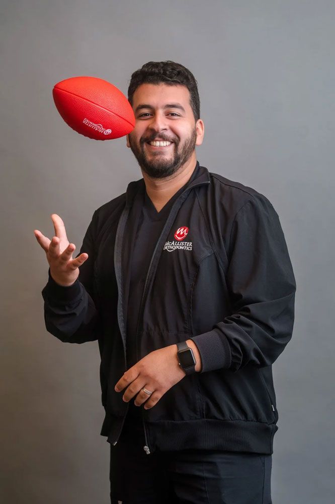 A woman in a black jacket is holding a volleyball in her hands.