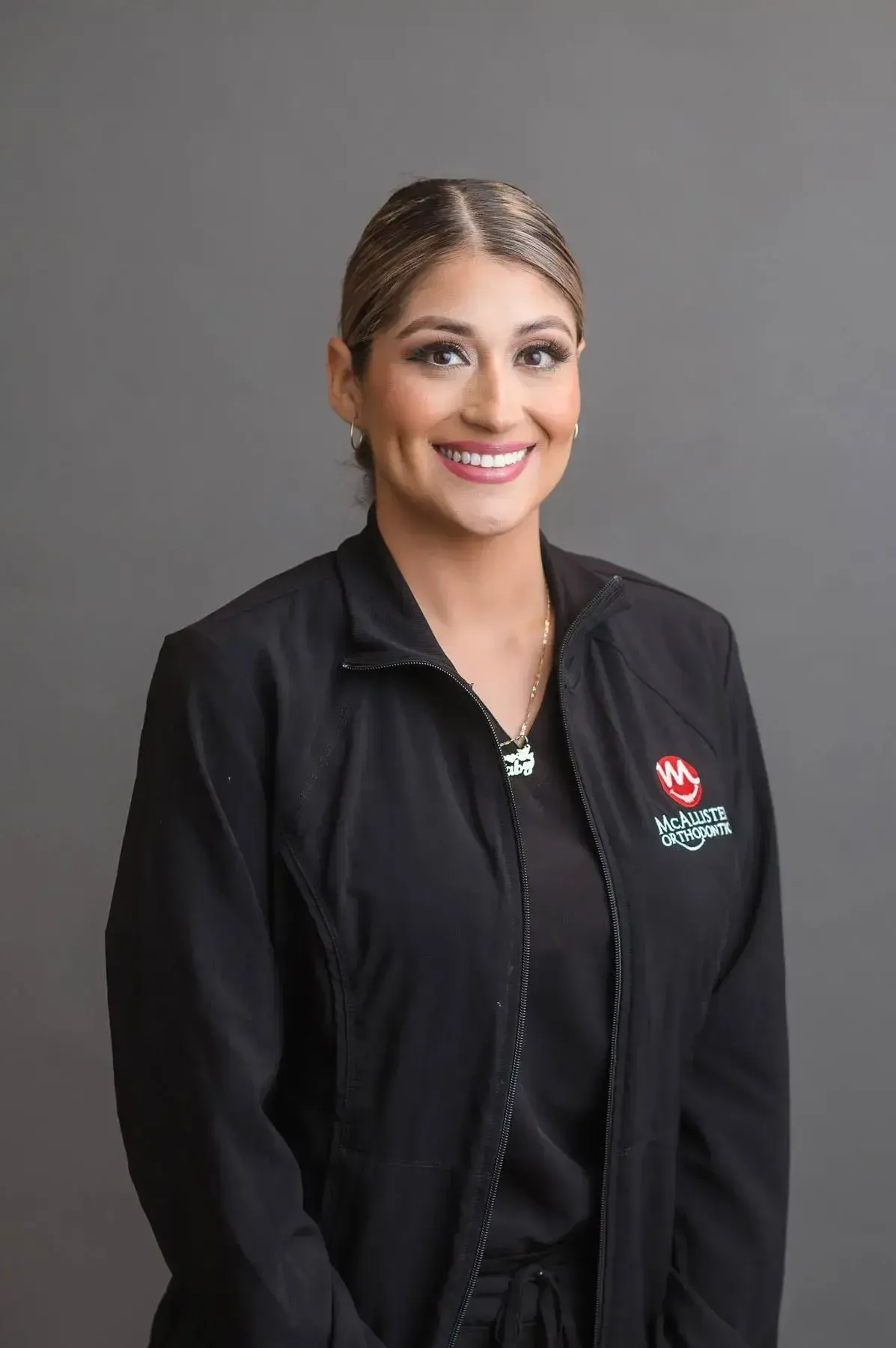 A woman is wearing a black jacket and smiling for the camera.