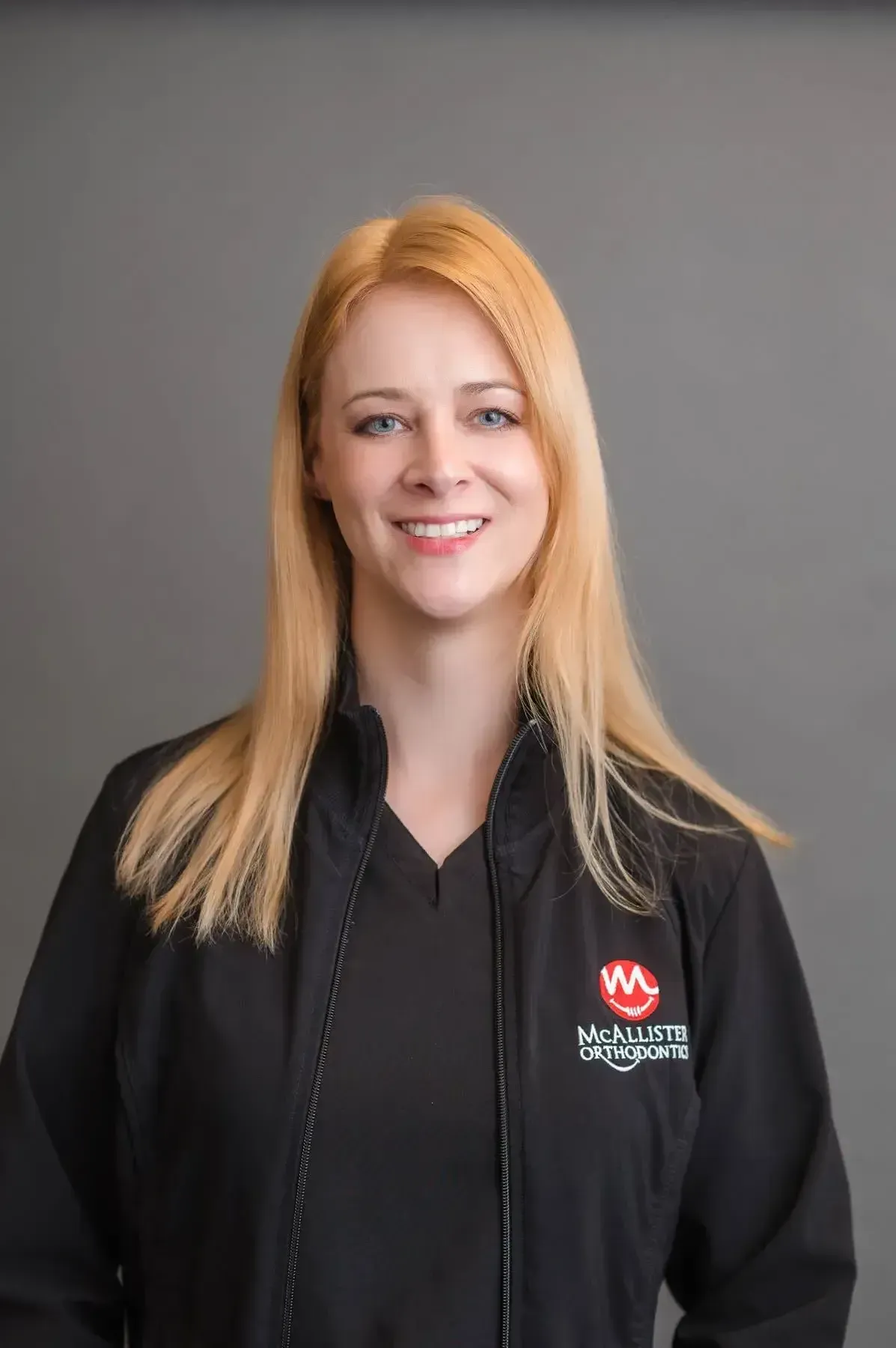 A woman is wearing a black jacket and smiling for the camera.