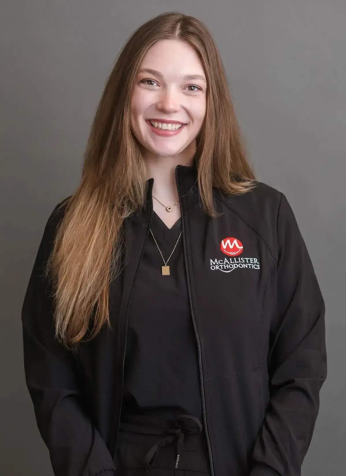 A young woman is wearing a black jacket and smiling.