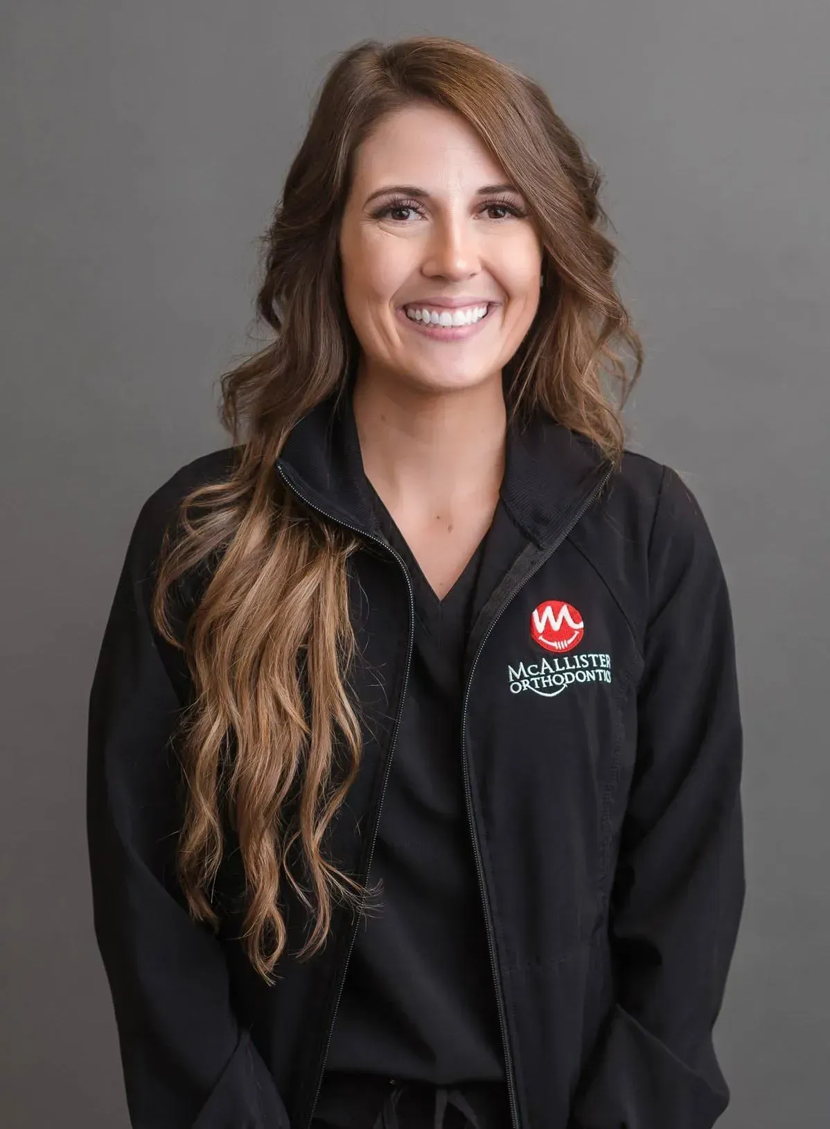 A woman is wearing a black jacket and smiling for the camera.