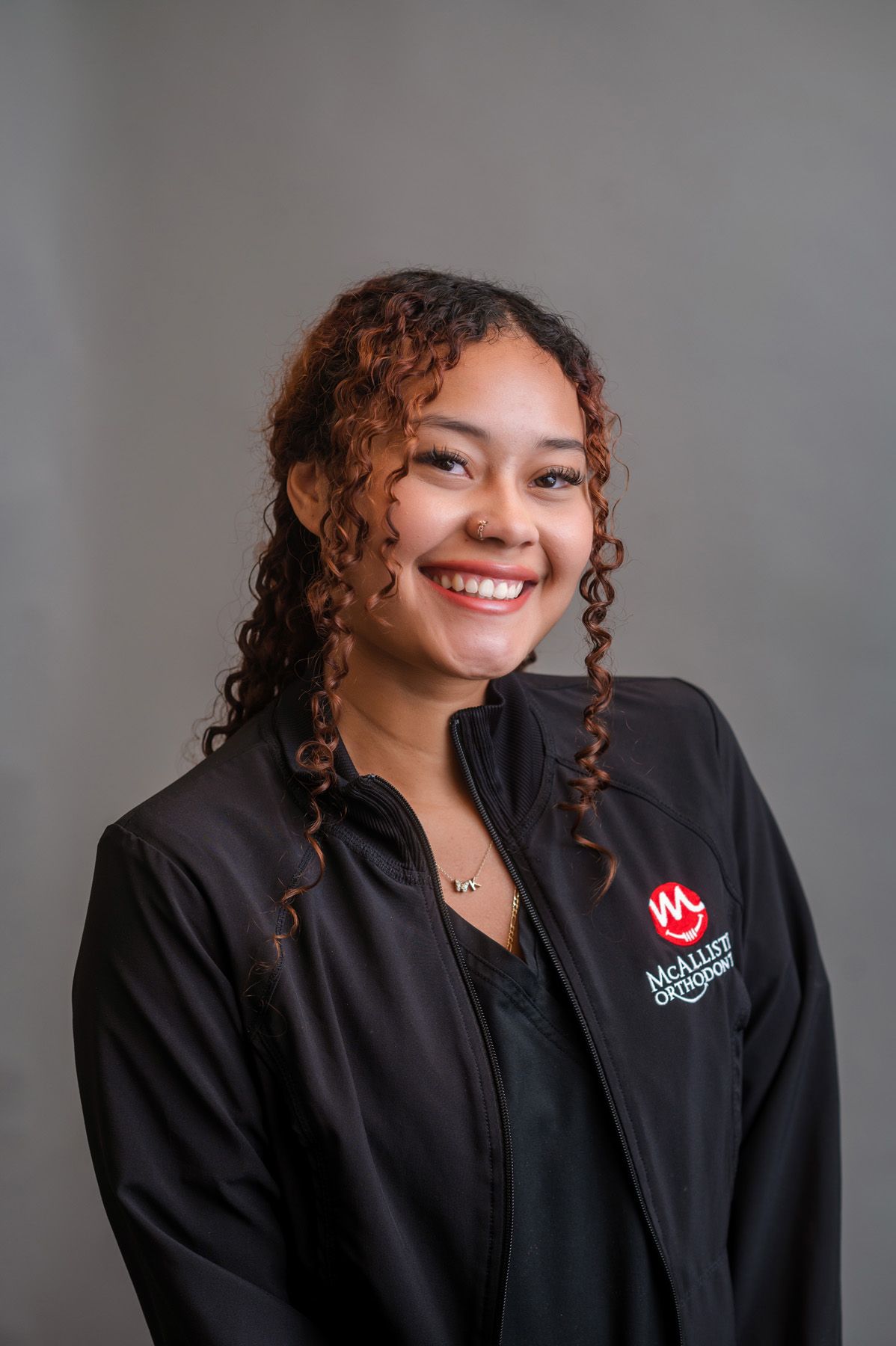 A woman is wearing a black jacket and smiling for the camera.