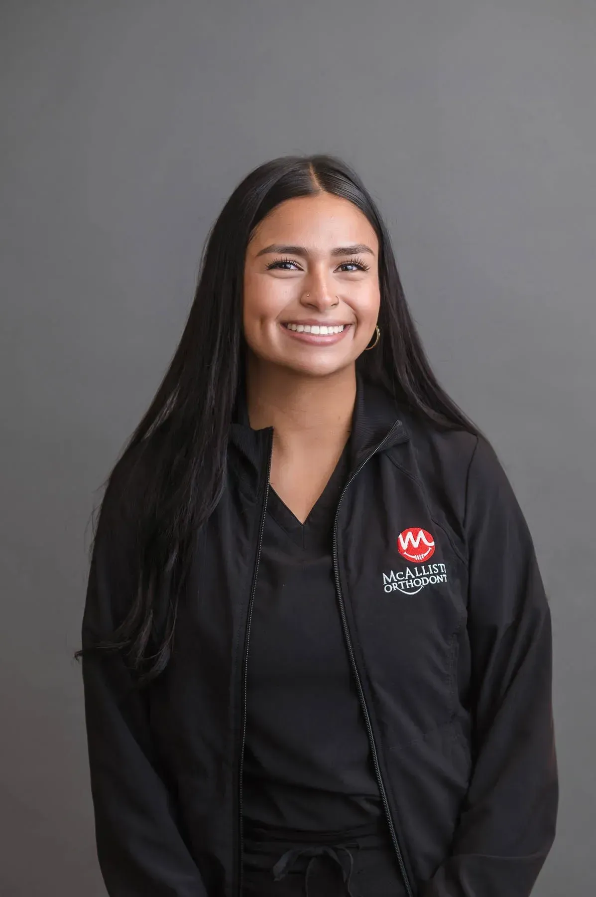 A woman is wearing a black jacket and smiling for the camera.