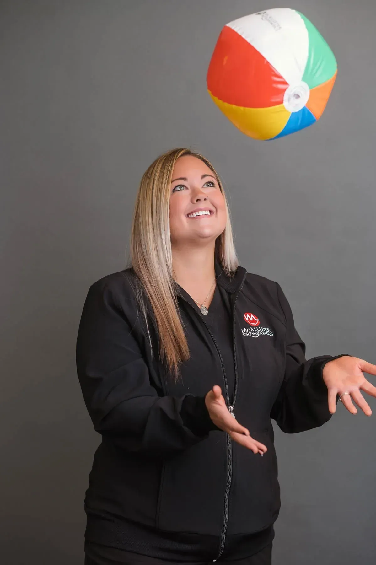 A woman is throwing a beach ball in the air.