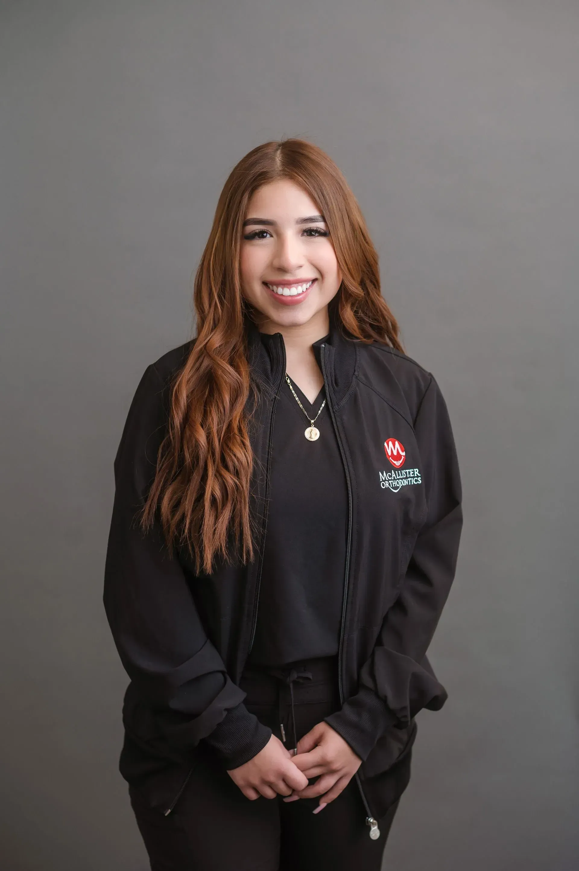 A woman is wearing a black jacket and smiling for the camera.