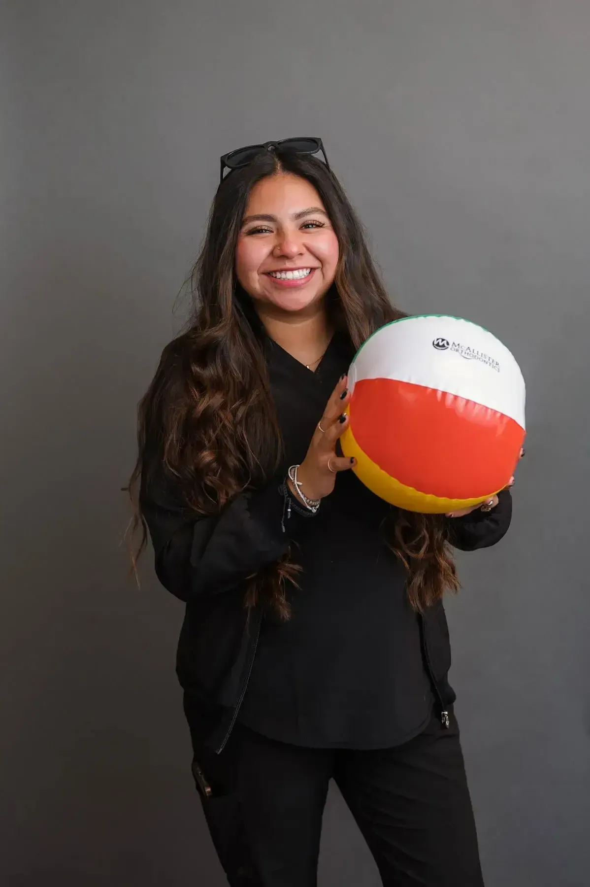 A woman is holding a beach ball and smiling.