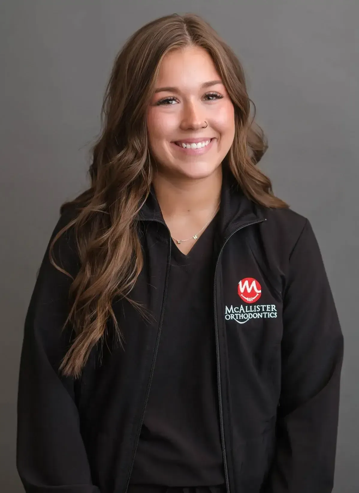 A woman wearing a black jacket and a black shirt is smiling.