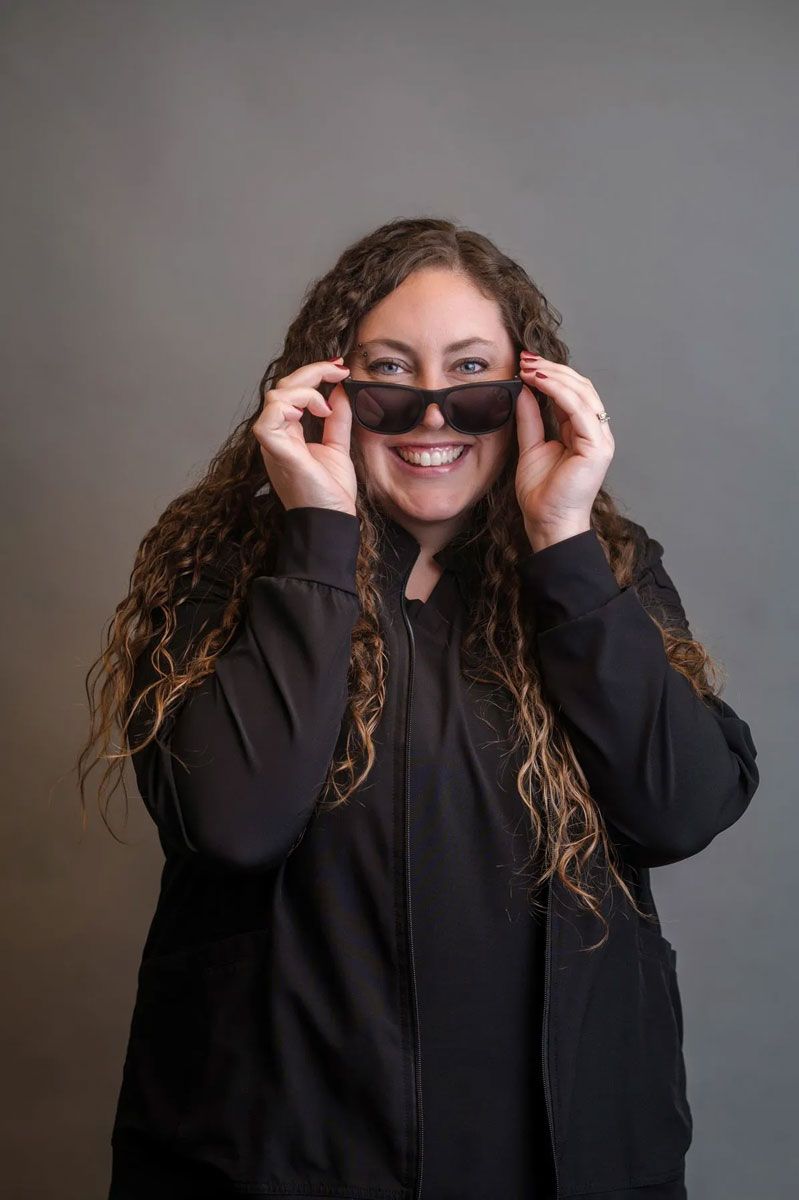 A woman in a black jacket is holding a volleyball in her hands.