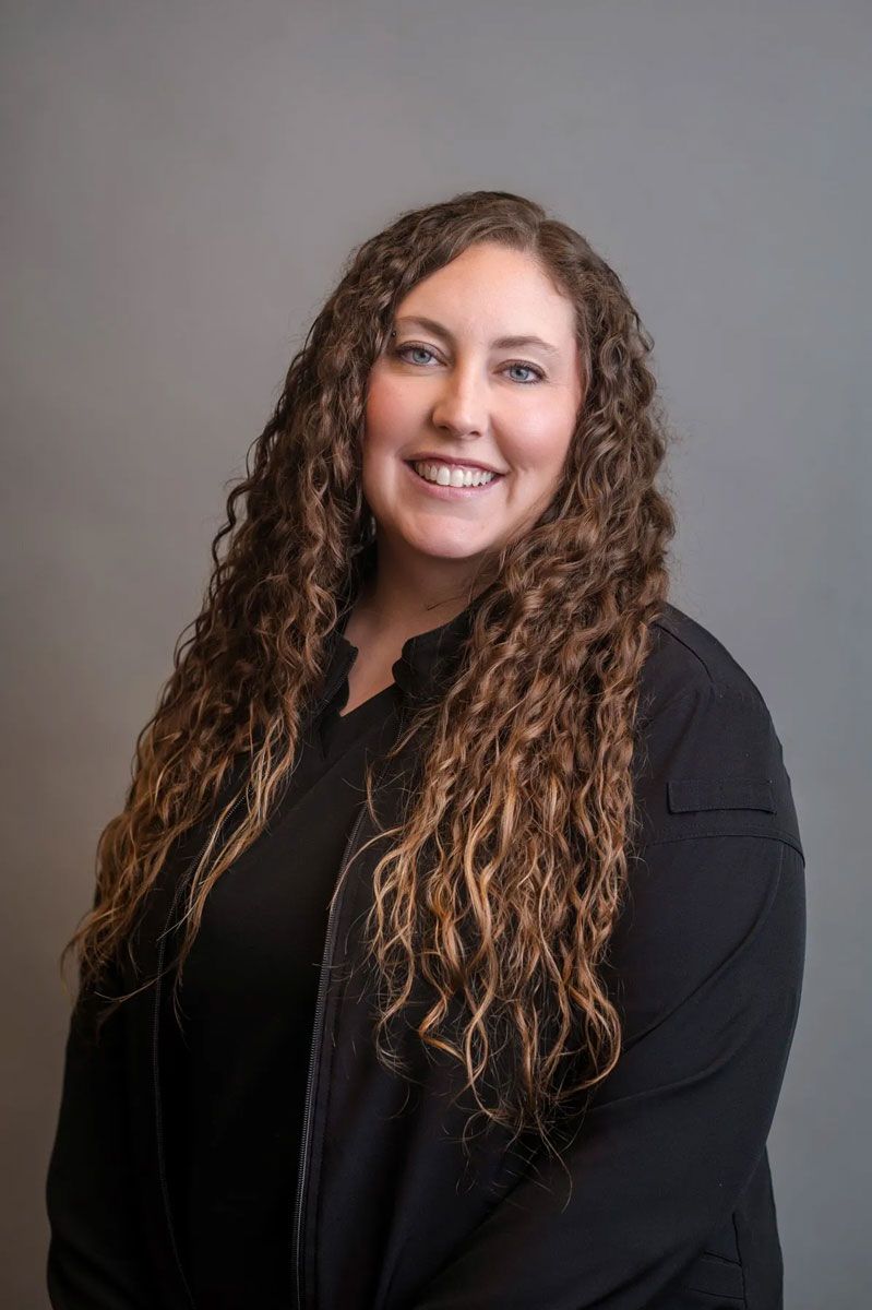A woman is wearing a black jacket and smiling for the camera.