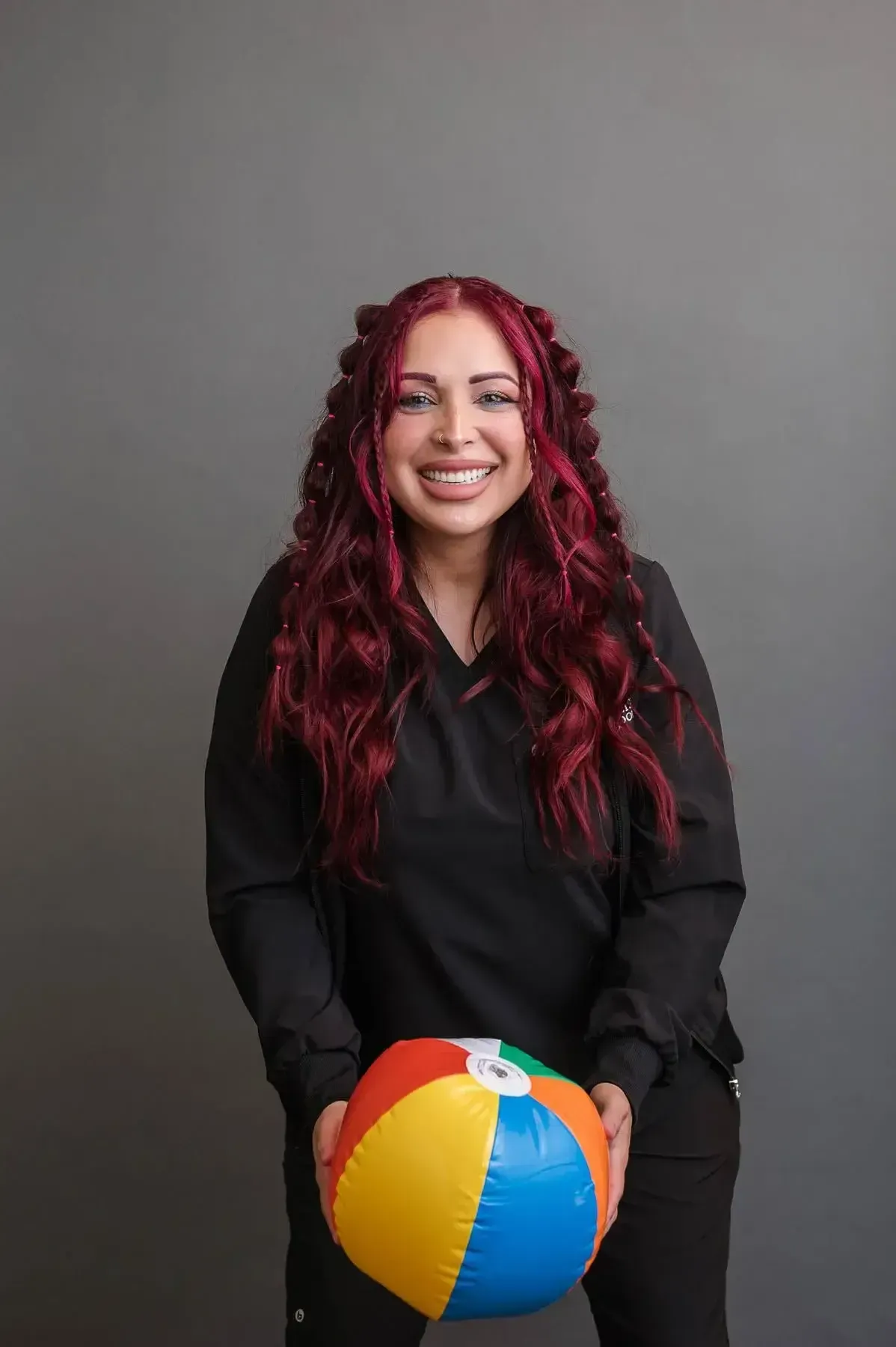 A woman with red hair is holding a beach ball and smiling.