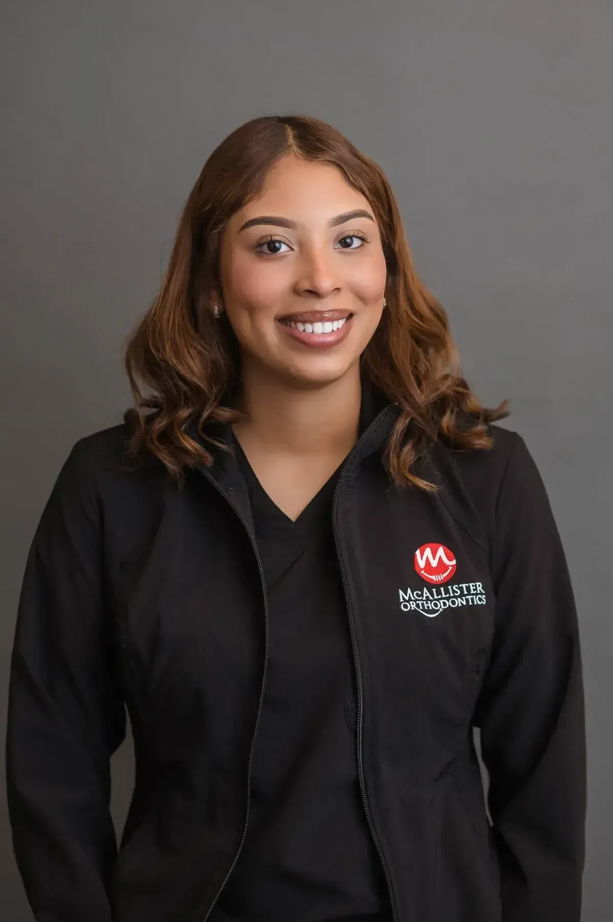 A woman is wearing a black jacket and smiling for the camera.