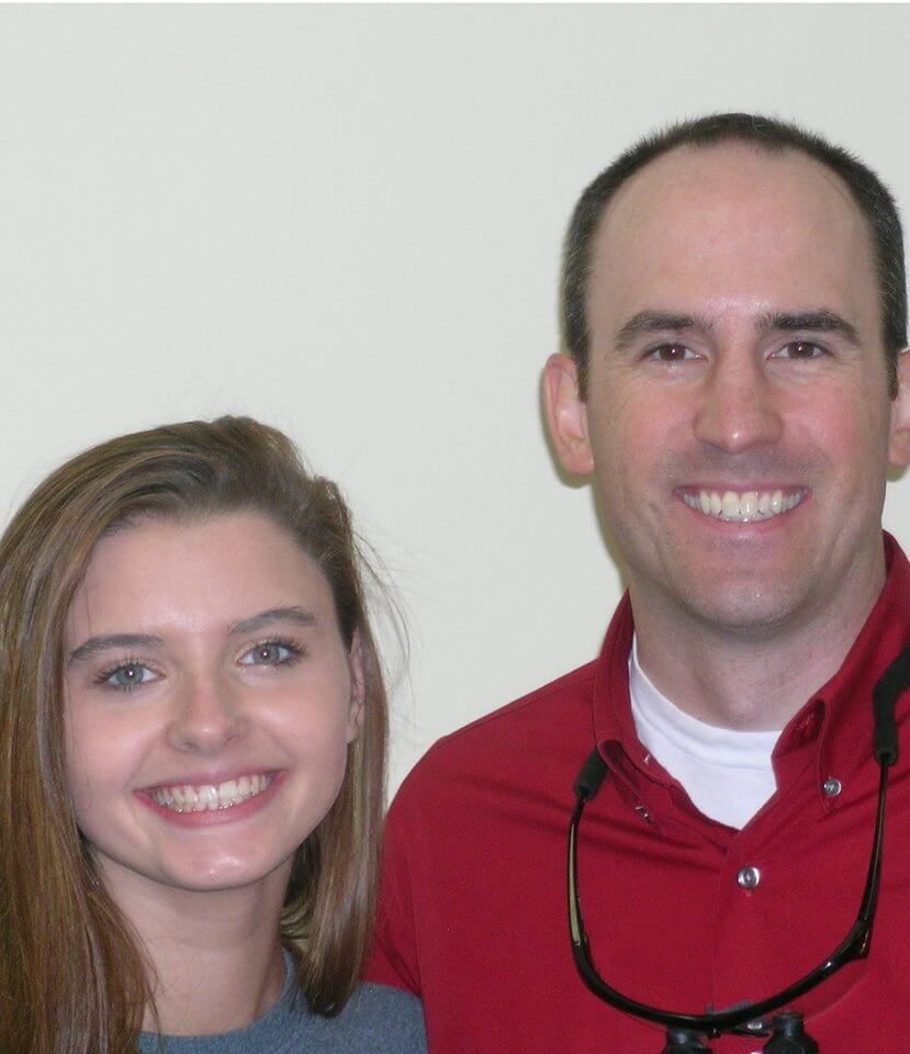 A man with a stethoscope around his neck smiles next to a woman