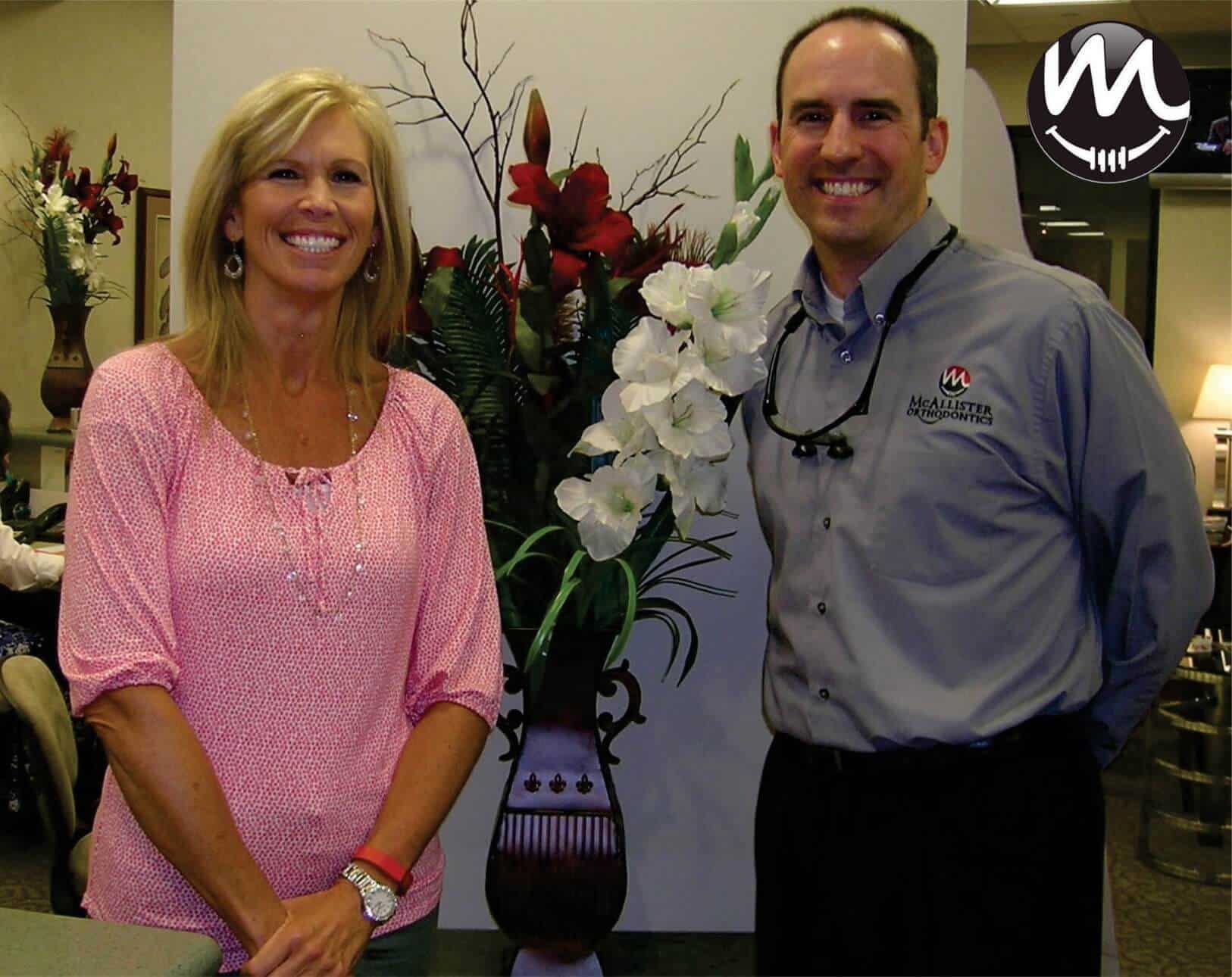 A man and a woman standing next to a vase of flowers