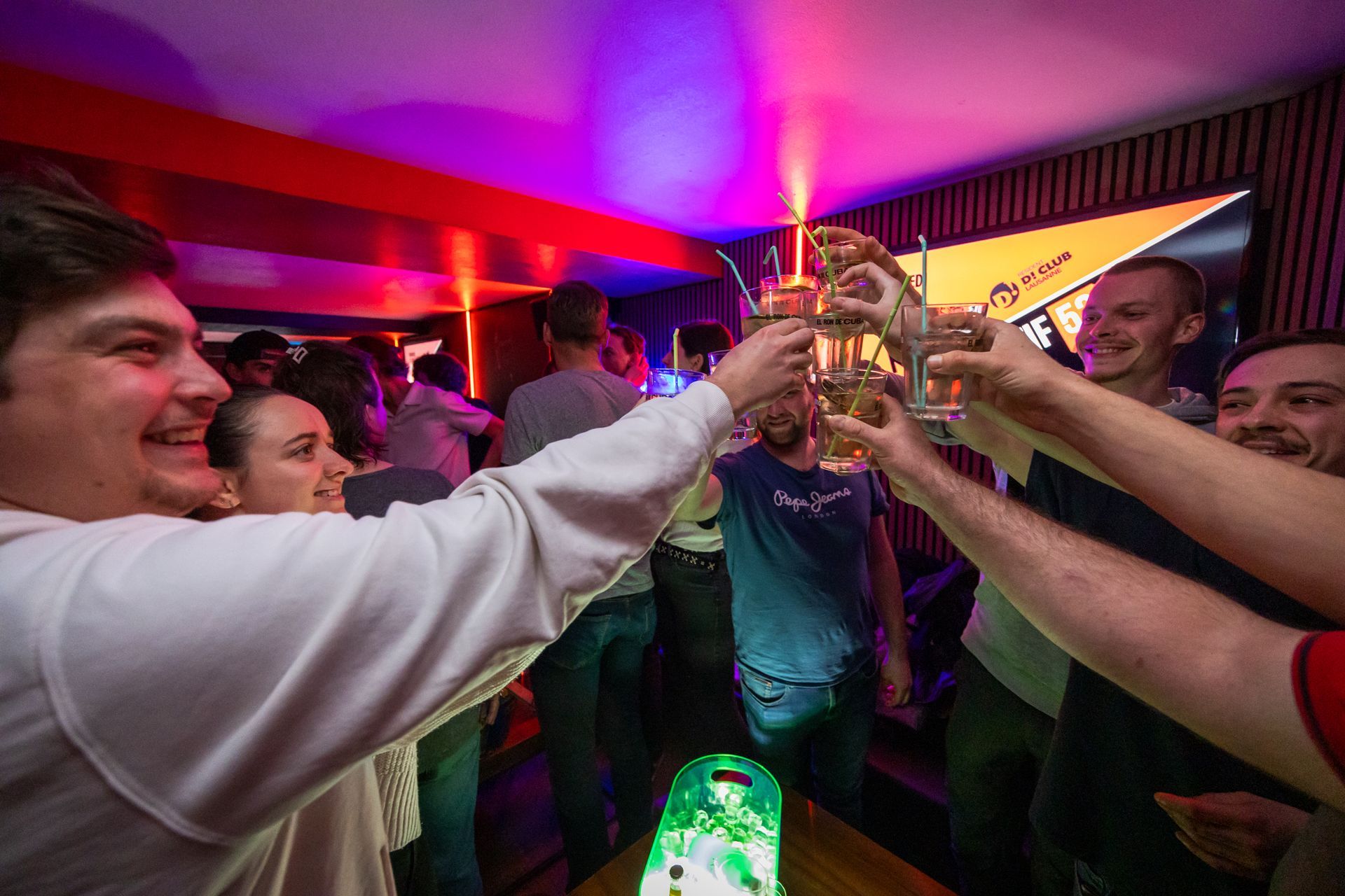 Un groupe de personnes trinquent avec leurs verres dans un bar.