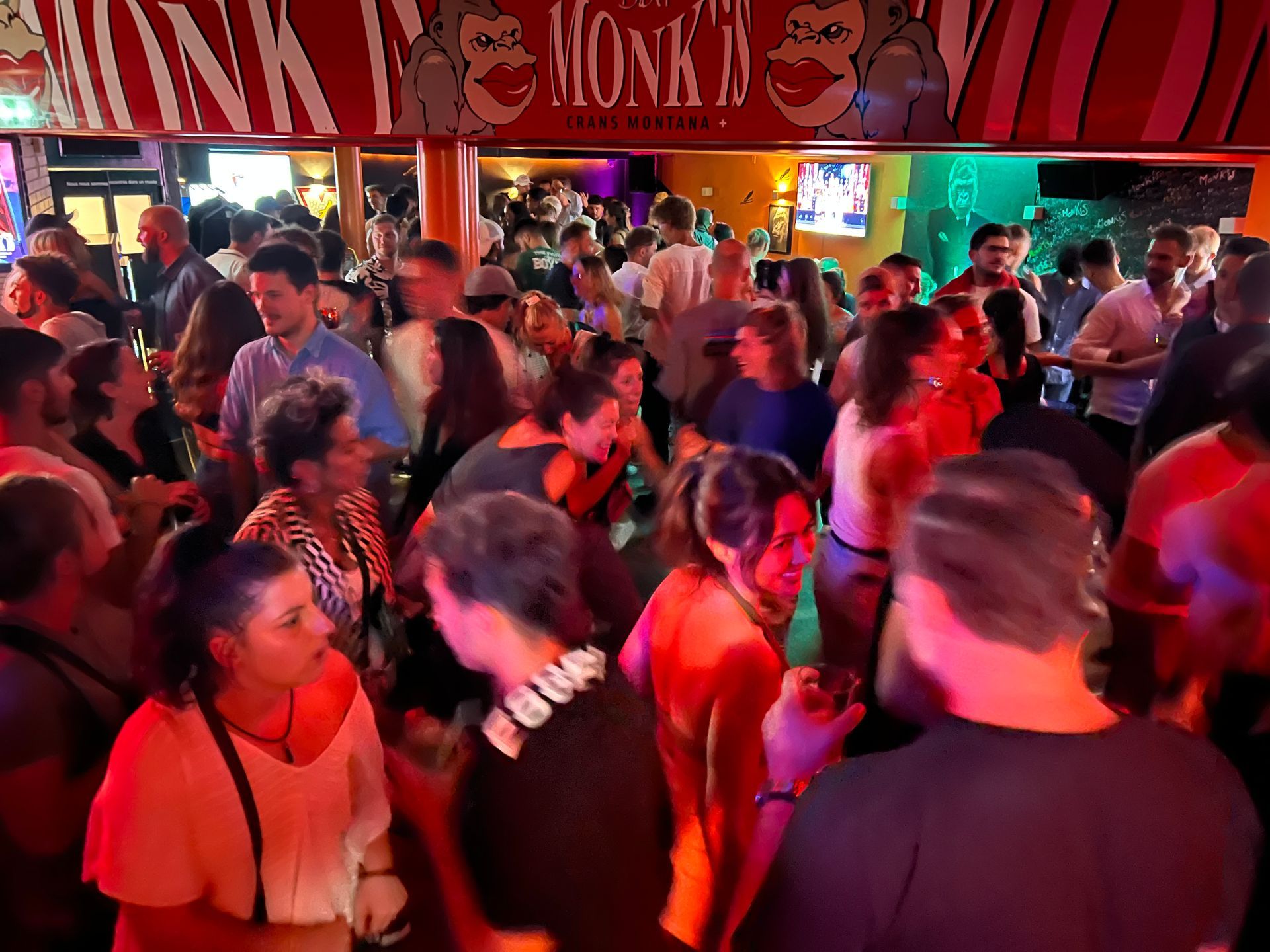 Une foule de personnes est rassemblée sous un panneau indiquant moine