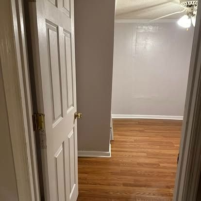 A hallway with hardwood floors and a ceiling fan in a house.