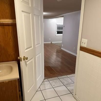 A bathroom with a sink and a door open leading to a living room.